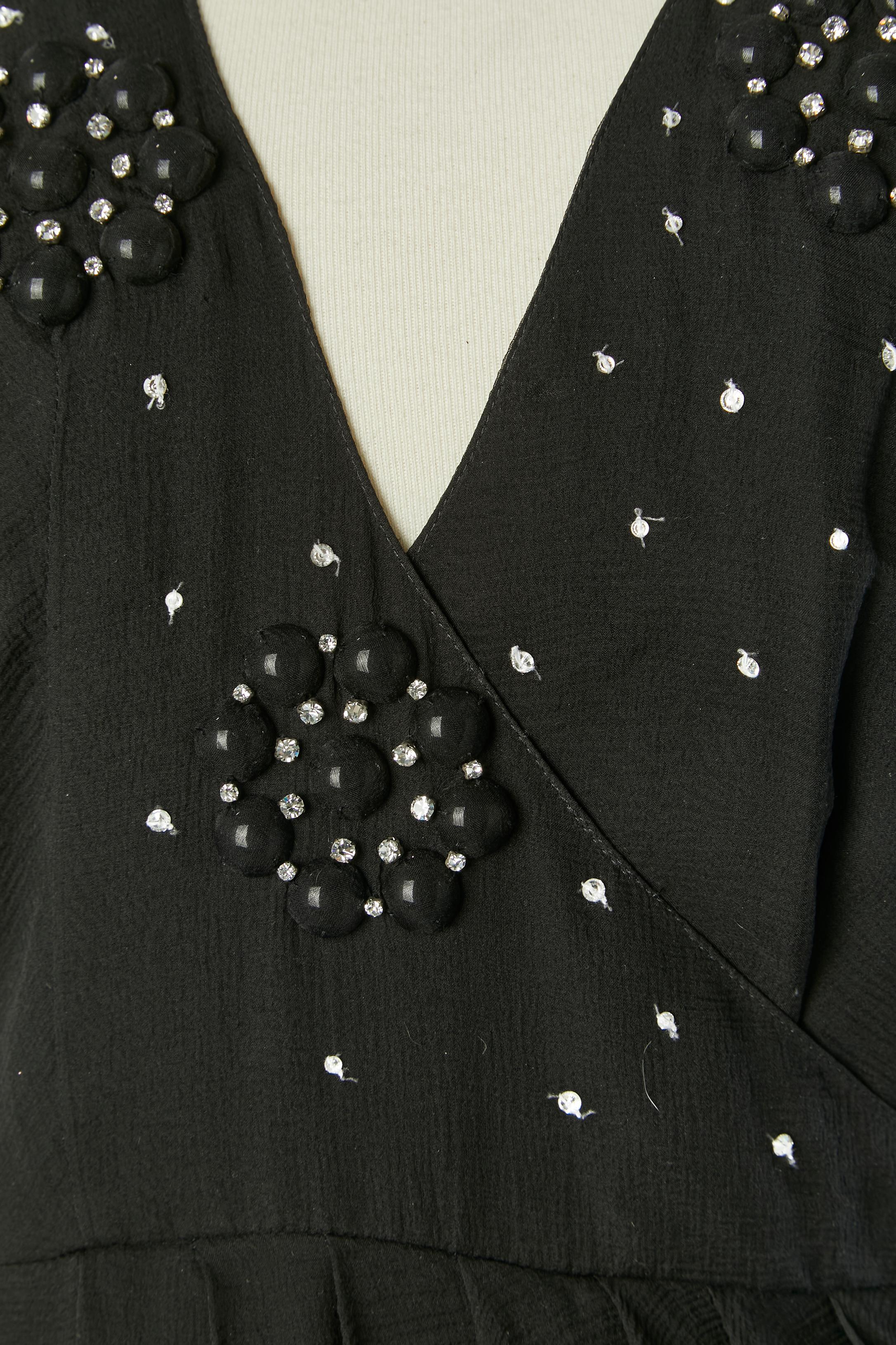 Schwarzes ärmelloses Seiden-Cocktailkleid mit Strassverzierung. Seidenfutter. Im Brustbereich gewickelt und in der Taille drapiert. Stoff Knopf und Knopfloch auf der linken Seite. 
GRÖSSE 36 (Fr) 4 (US) 