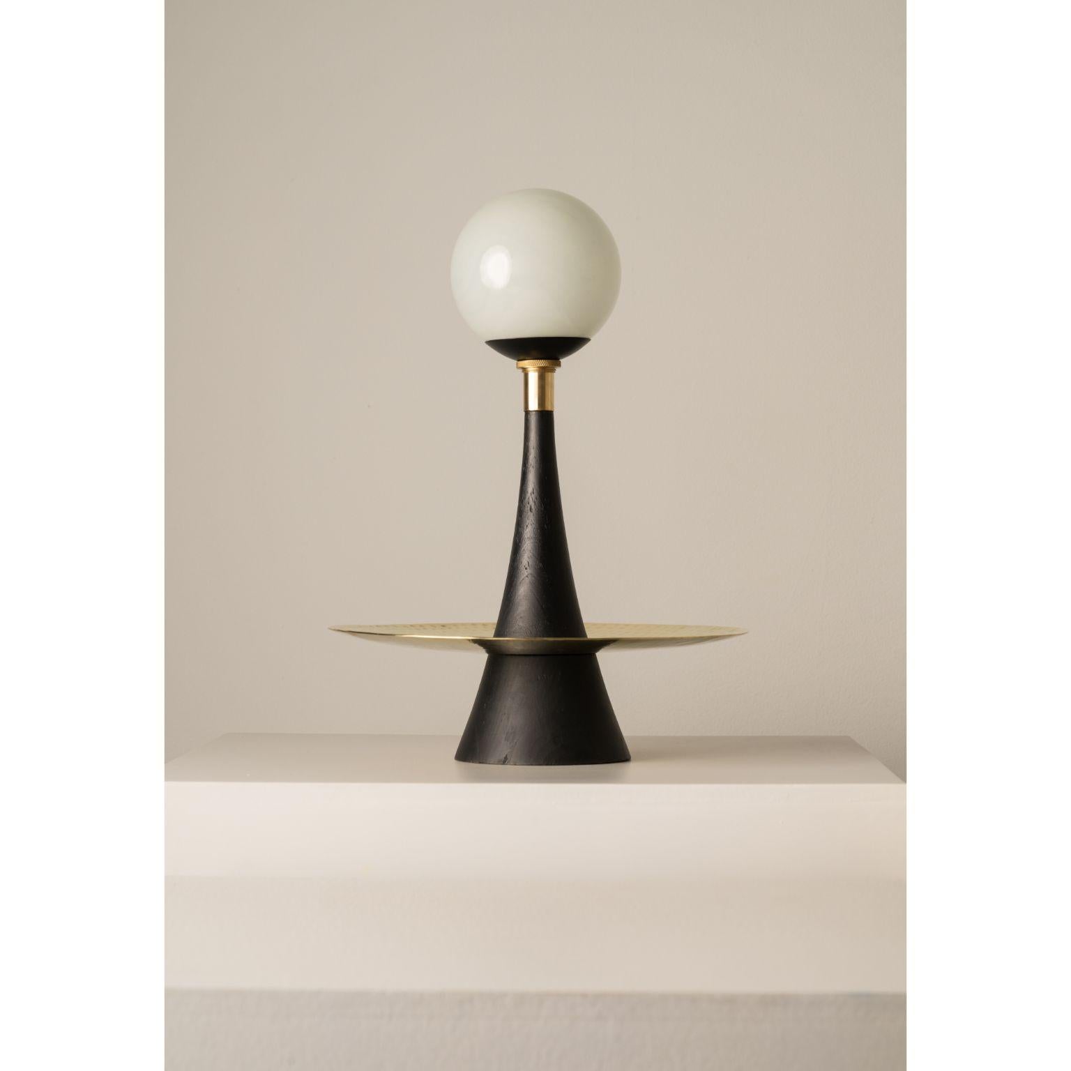 Black Sonic Table Lamp by Isabel Moncada
Dimensions: Ø 30.5 x H 46 cm.
Materials: Turned pine wood in matte black finish, hand-forged brass plate and blown glass globes.

The graceful shape of this lamp takes inspiration from the futuristic-looking