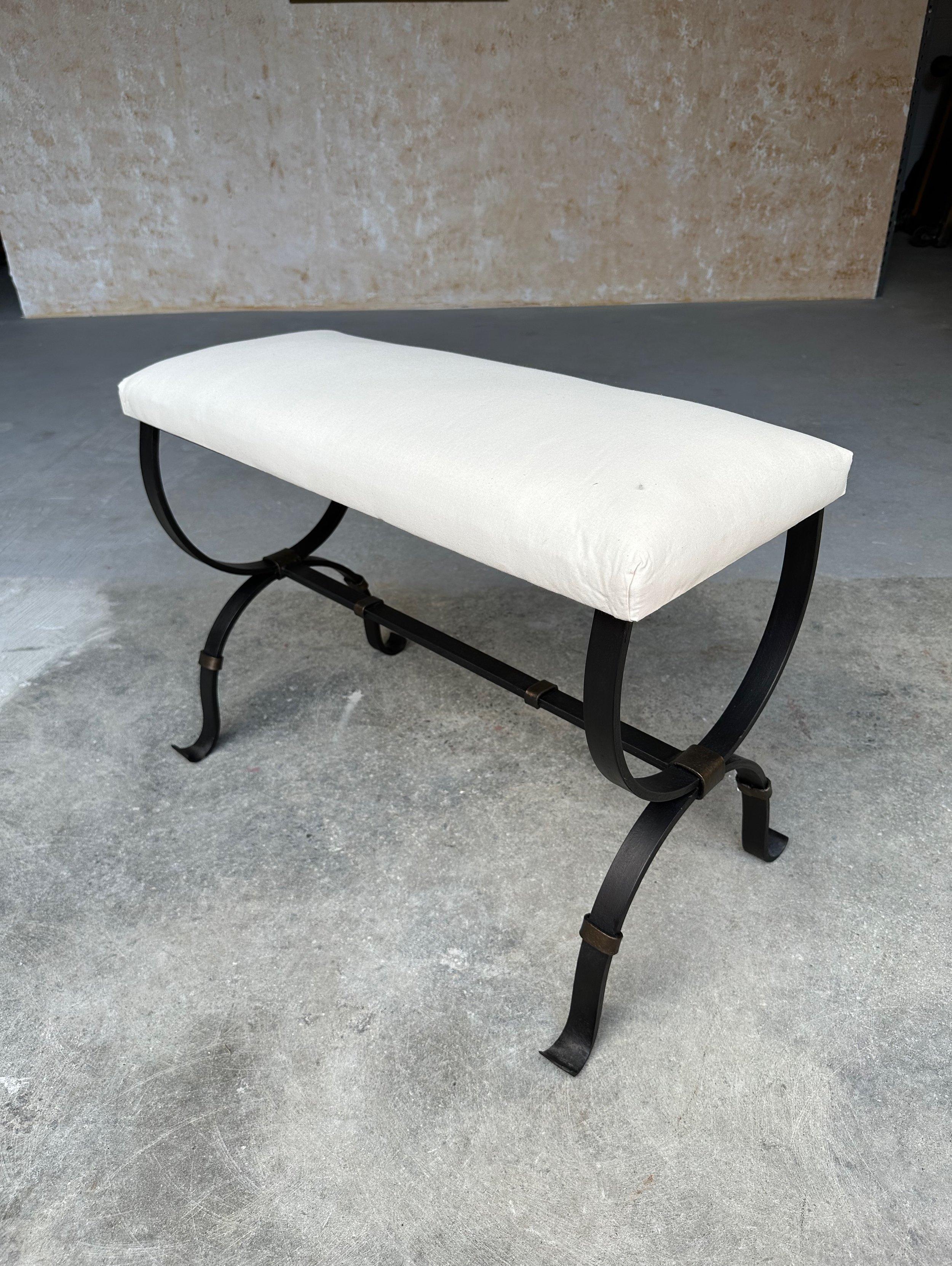 This elegant iron bench was recently made by skilled European artisans and features gently scrolled legs and stretcher with decorative band details. Handmade by expert craftsmen, it has a hand forged iron base with a hand applied matte black finish