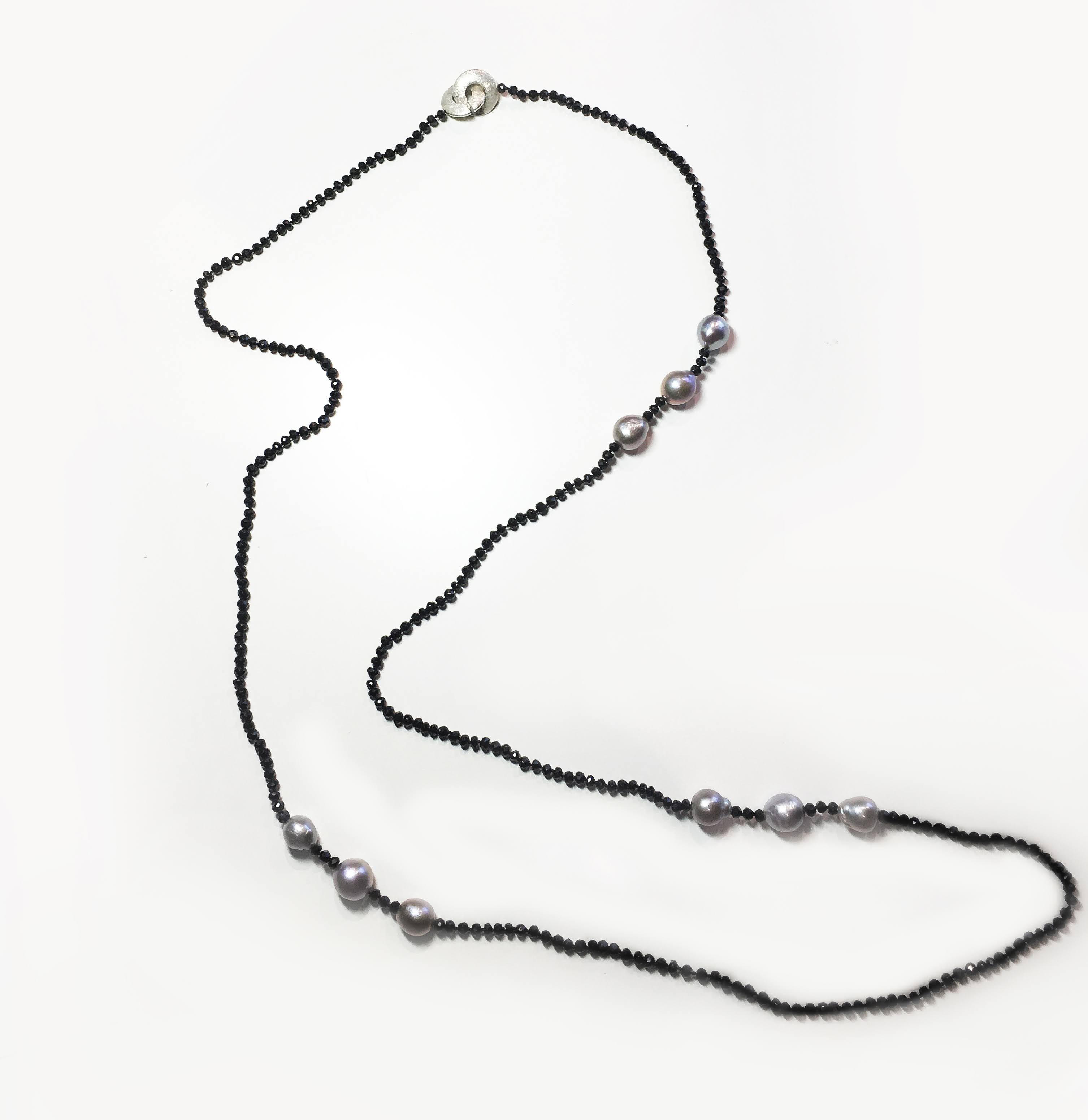 Add some chic sparkle and edge with this one-of-a-kind black spinel and grey baroque pearl long necklace with textured sterling silver interlocking clasp. Necklace is knotted between each bead. Can be worn single, double layered, or as a lariat.