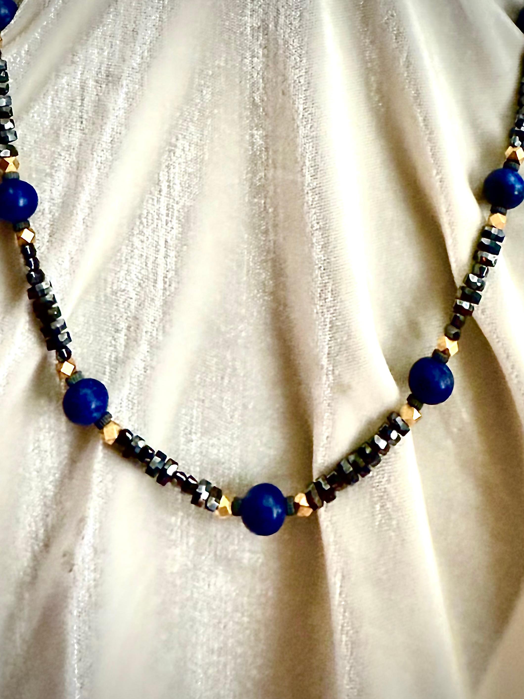 Chic and stunning single strand black, blue and gold gilt necklace. 

This opera length necklace consists of sparkling black faceted rondelle beads punctuated by stations of large deep blue matte finished lapis lazuli round beads. The lapis beads