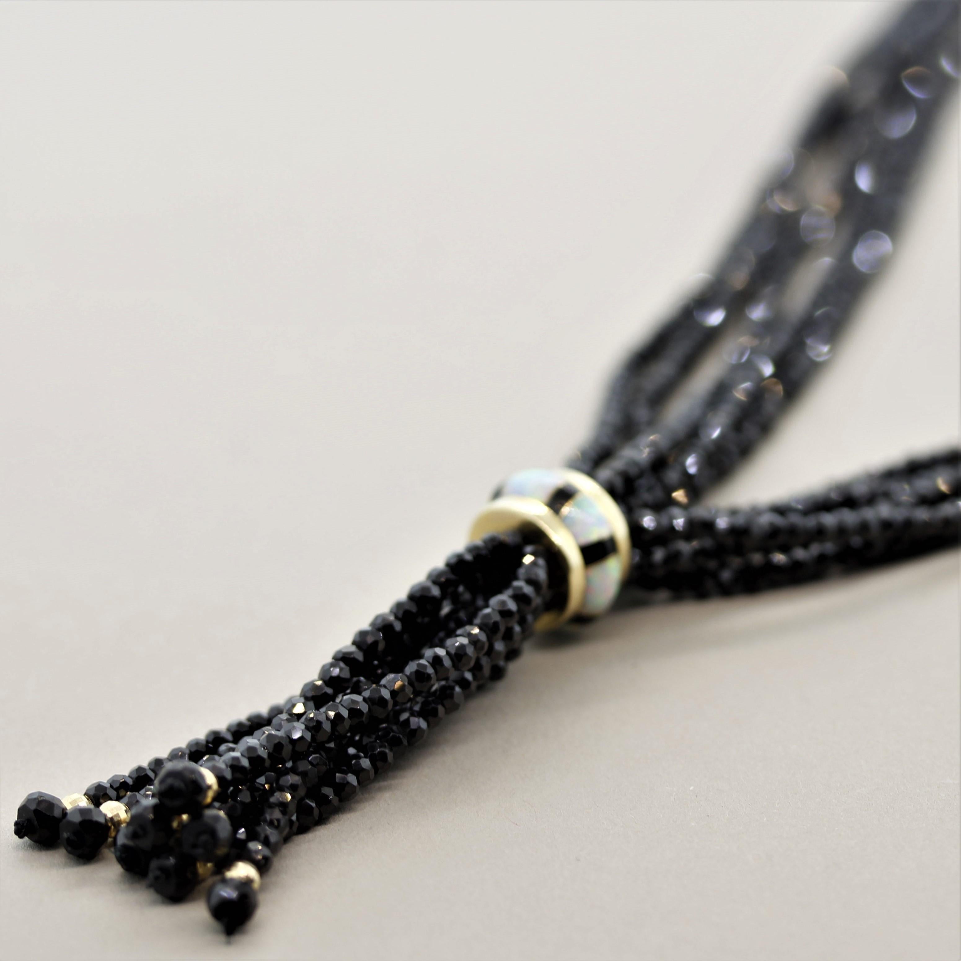 A stylish 5-strand necklace made of black spinel beads. They are joined together in the lower portion of the necklace by a gold band set with white opals with excellent play of color. The clasp is made in 14k yellow gold and ensures a safe