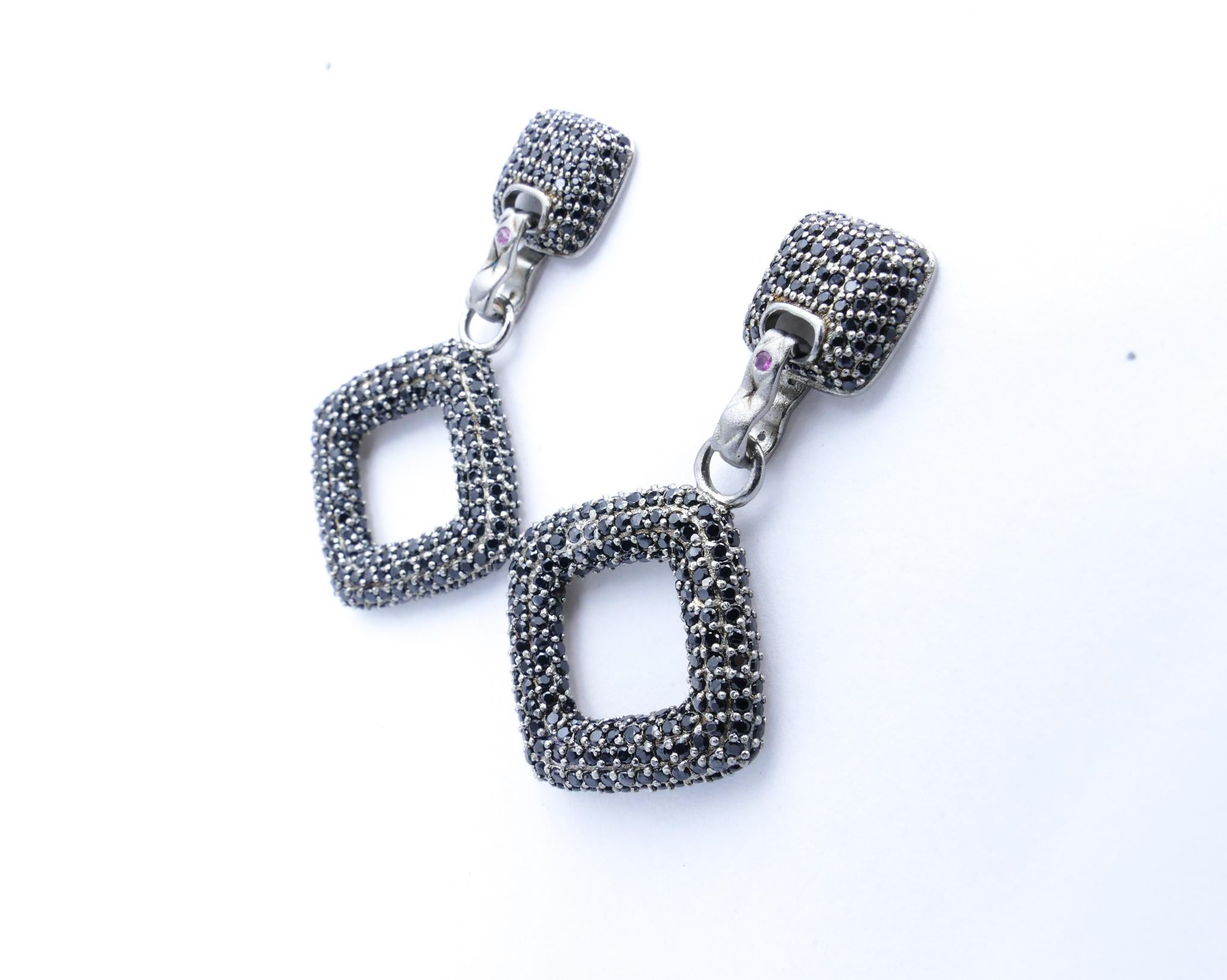 Set in Sterling Silver these Designer Earrings are so so smart. And very eye-catching.
Great for evening wear but smart even with a pair of jeans.
Designed pave style with hanging diamond shape squares at the bottom composed of glittery black Spinel