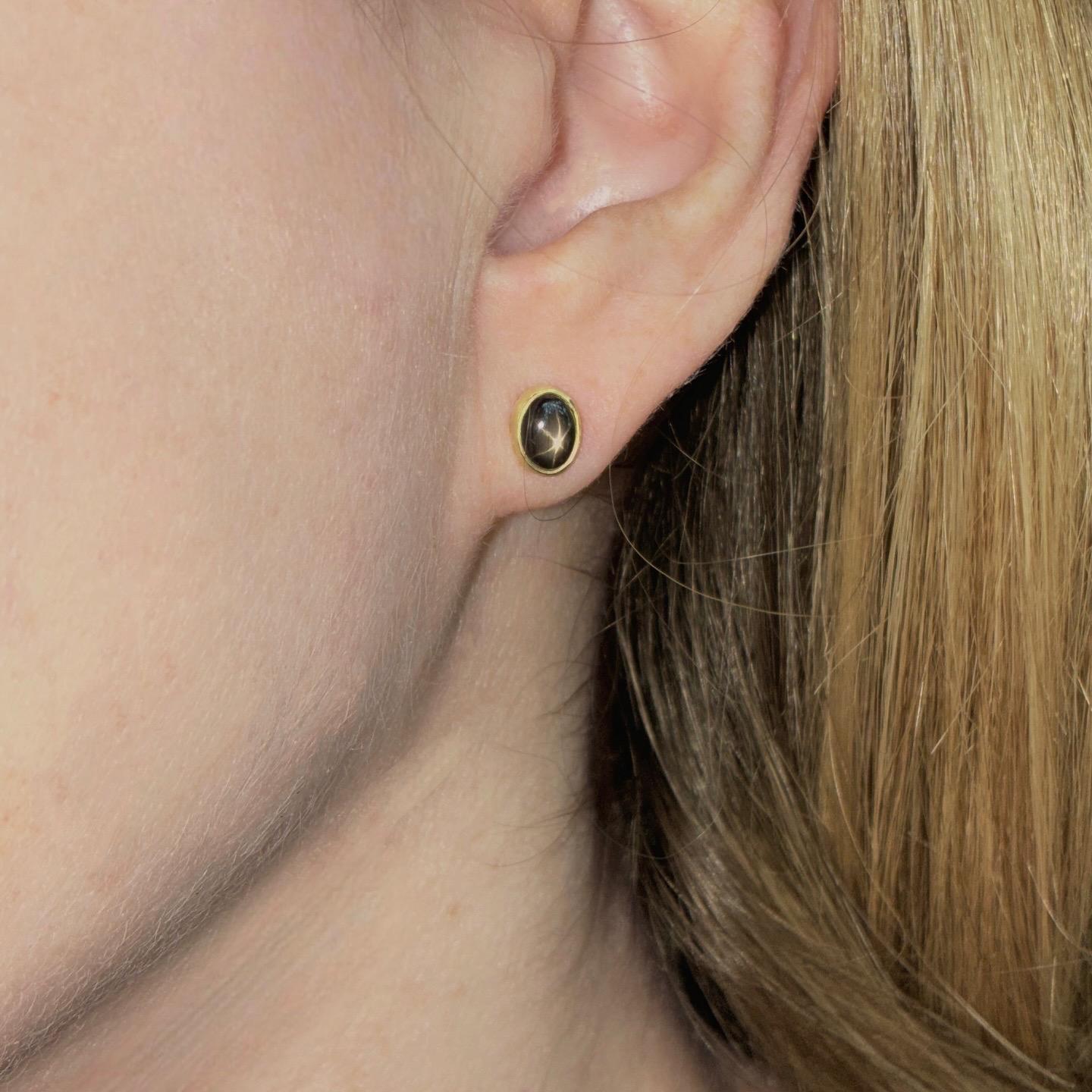 Boucles d'oreilles uniques fabriquées à la main par Monica Monica, joaillière, en or jaune 18 carats au fini mat, mettant en valeur une paire spectaculaire de saphirs ovales étoilés noirs avec phénomènes d'astérisme.

A propos de la pierre précieuse