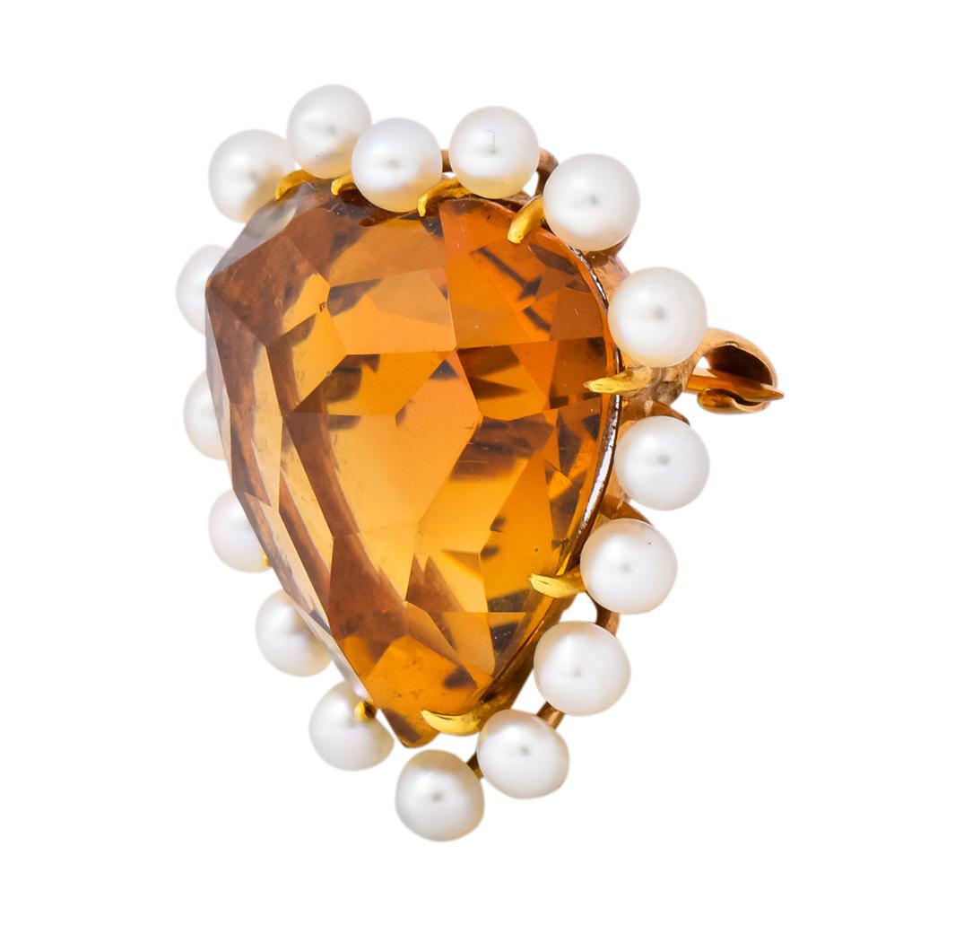 Centering a claw set heart-cut citrine measuring approximately 17.0 x 17.5 mm, transparent medium-light brownish-orange in color

Surrounded by round natural pearls measuring approximately 2.7 mm, cream in body color with very good luster and very