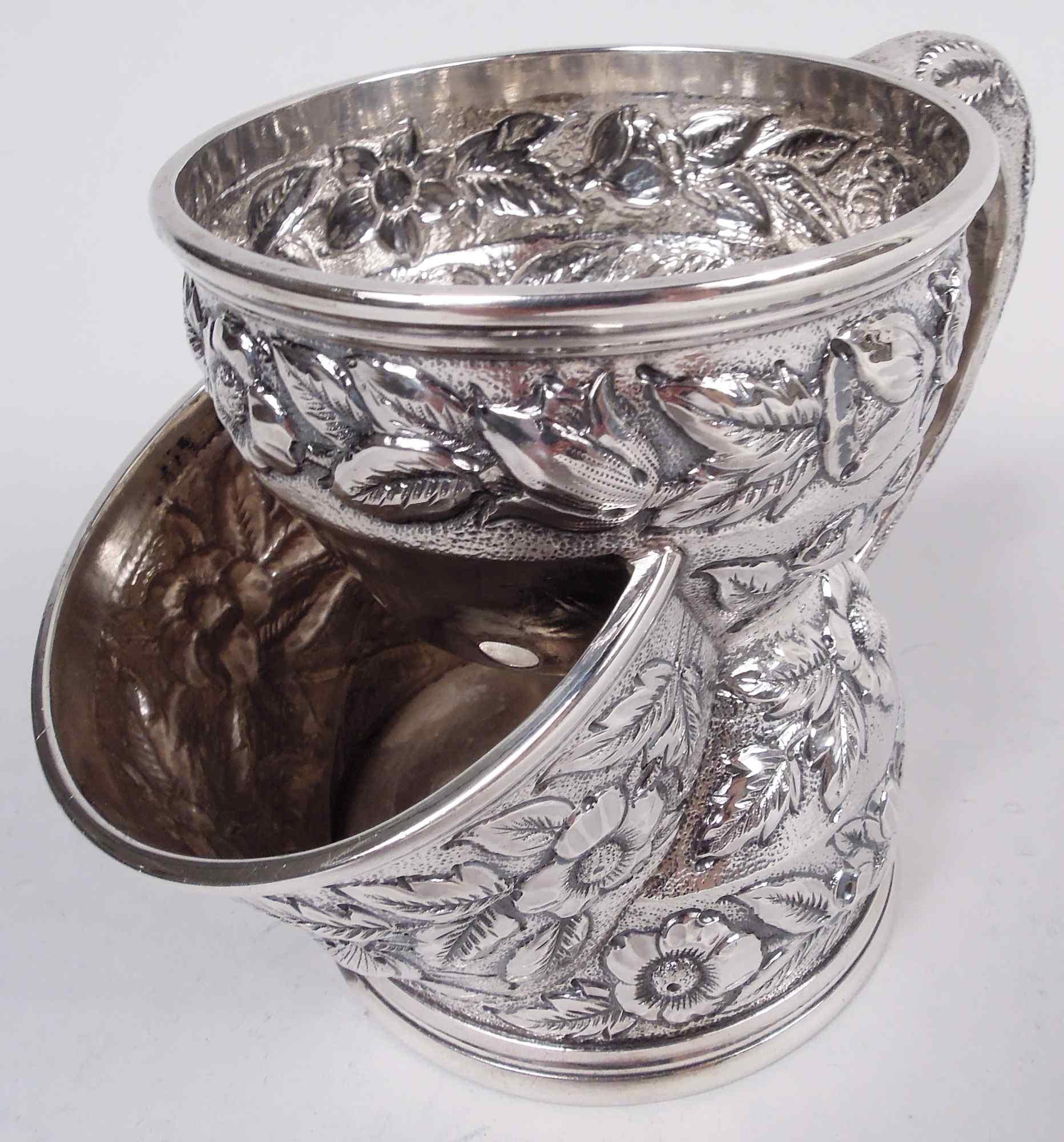 American Victorian sterling silver shaving mug, ca 1880. Curved and waisted with pierced top bowl and second projecting bowl for brush. Frond and flower repousse. Cast scroll handle has same motif. Marked “Black, Starr & Frost / New-York /