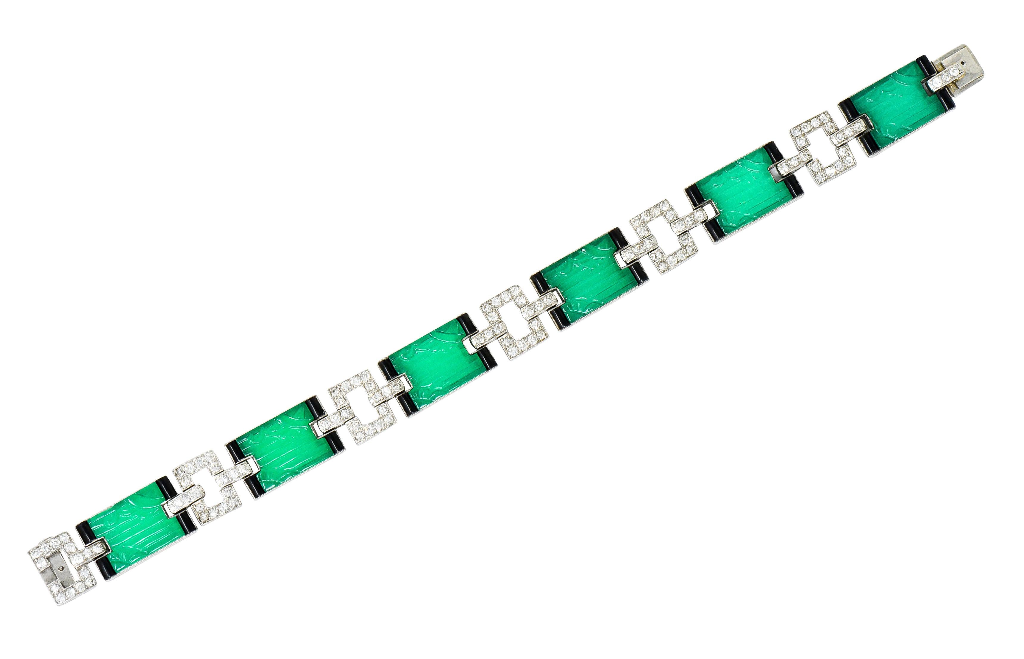 Link style bracelet featuring rectangular links bezel set with deeply ridged chrysoprase chalcedony, incredibly matched and translucent bluish-green

With barreled enamel accents at each corner, opaque and black with some loss; consistent with age,