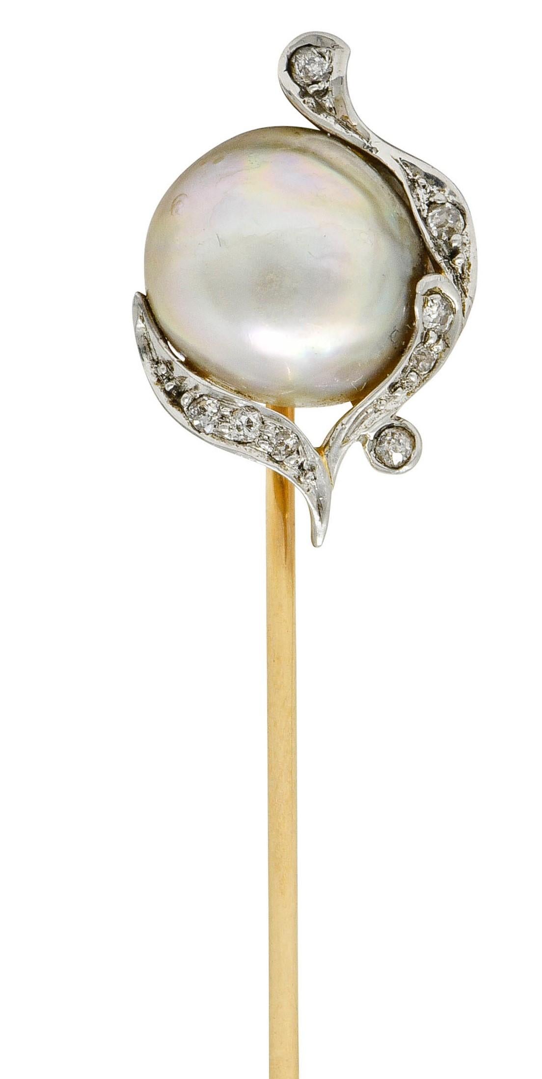 Centering a rounded baroque pearl measuring approximately 10.5 mm

Gray body color with strong spectral iridescence and good luster

Surrounded by organically rendered whiplash accented by old European cut diamonds

Weighing in total approximately