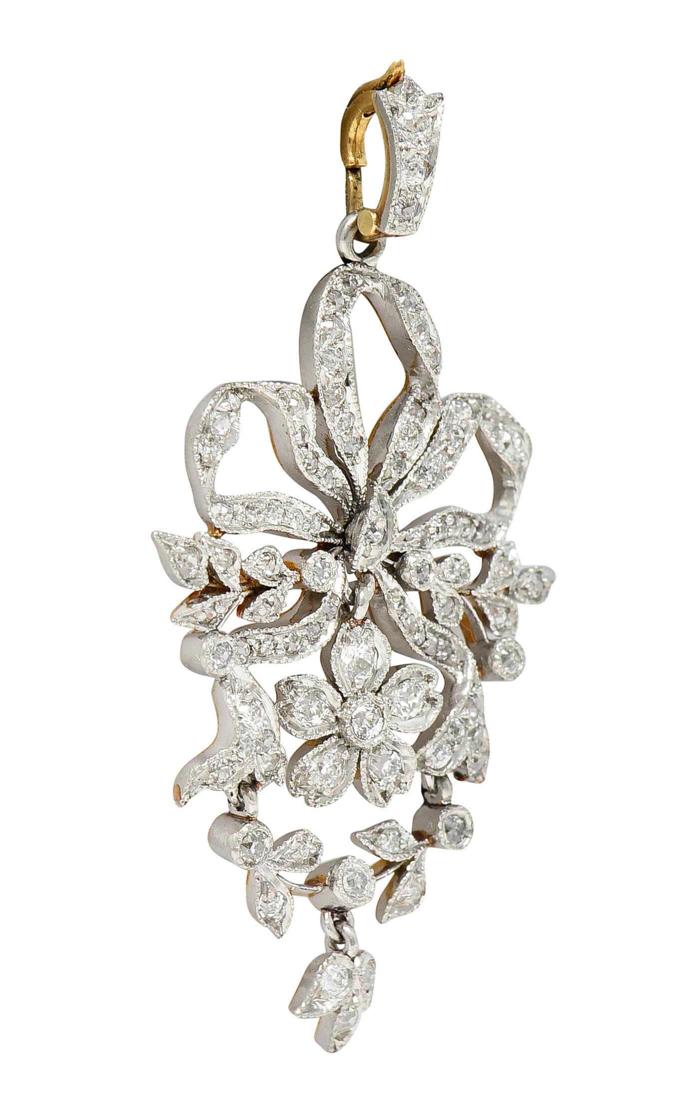 Enhancer pendant is designed as a ribboned bow centering an articulated floral drop. Suspending an articulated laurel foliate surround with drop. Accented throughout by old European cut diamonds. Weighing in total approximately 1.30 carats - G to J
