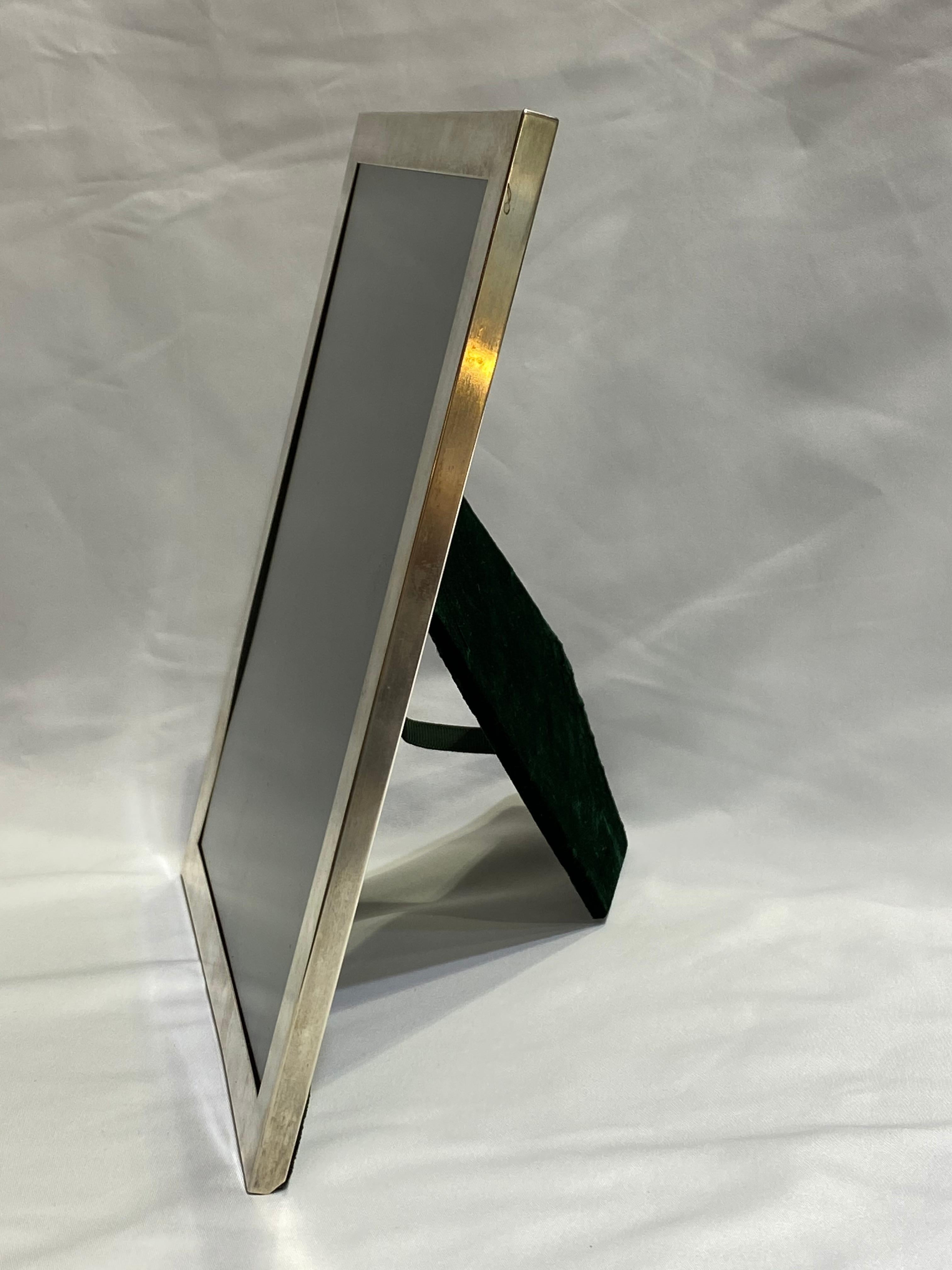 Product details:

Circa 1920's.
Featuring sterling silver frame with glass cover and green velvet closure on the back with a leg for standing and a bail for hanging the frame. The width of the silver frame is 0.63