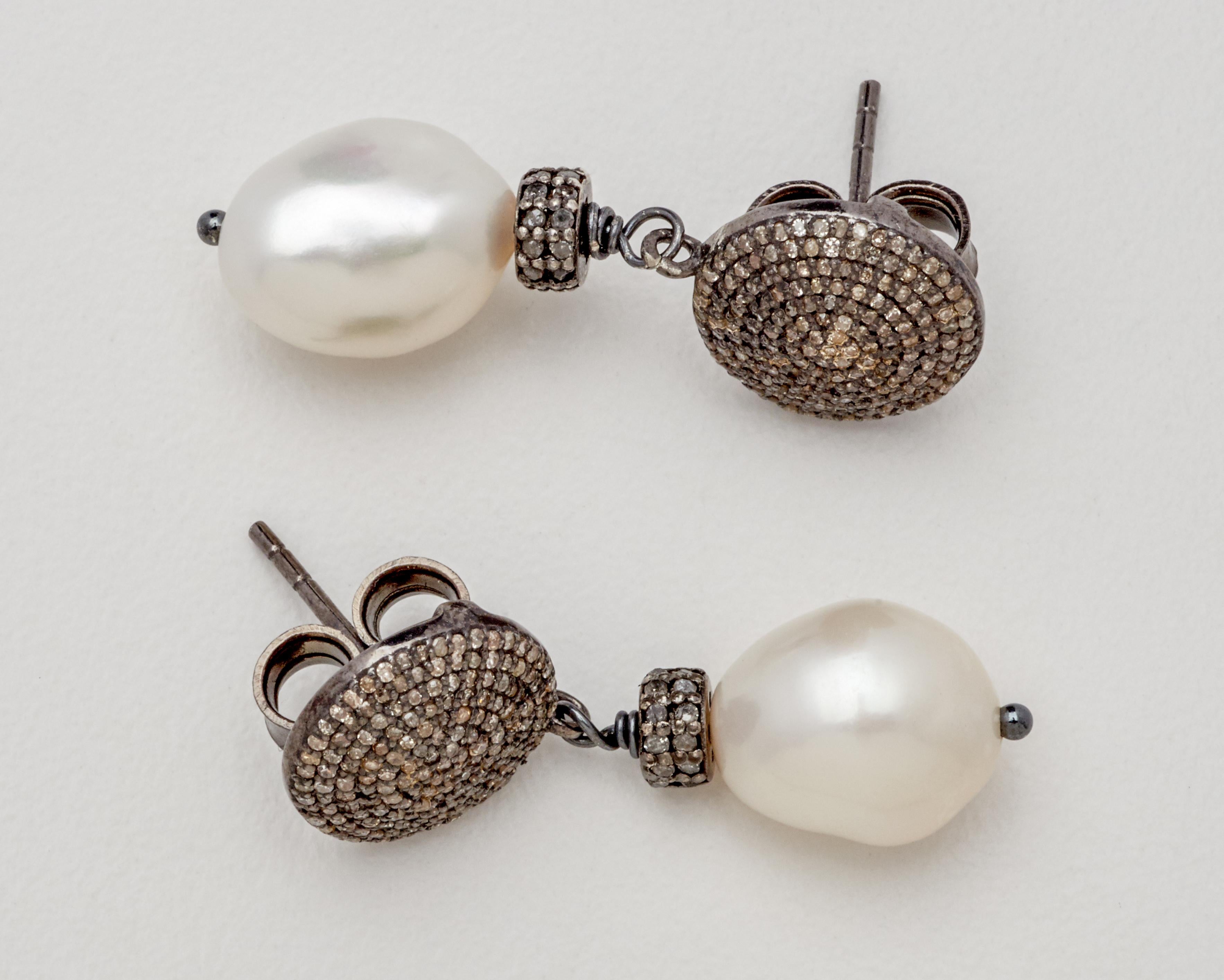Simply elegant earrings for every special occasion. Each has an artful, naturally shaped white 9 mm x 12 mm baroque pearl drop giving the pair tasteful movement. Newly crafted of diamond encrusted round sterling silver button studs measuring one