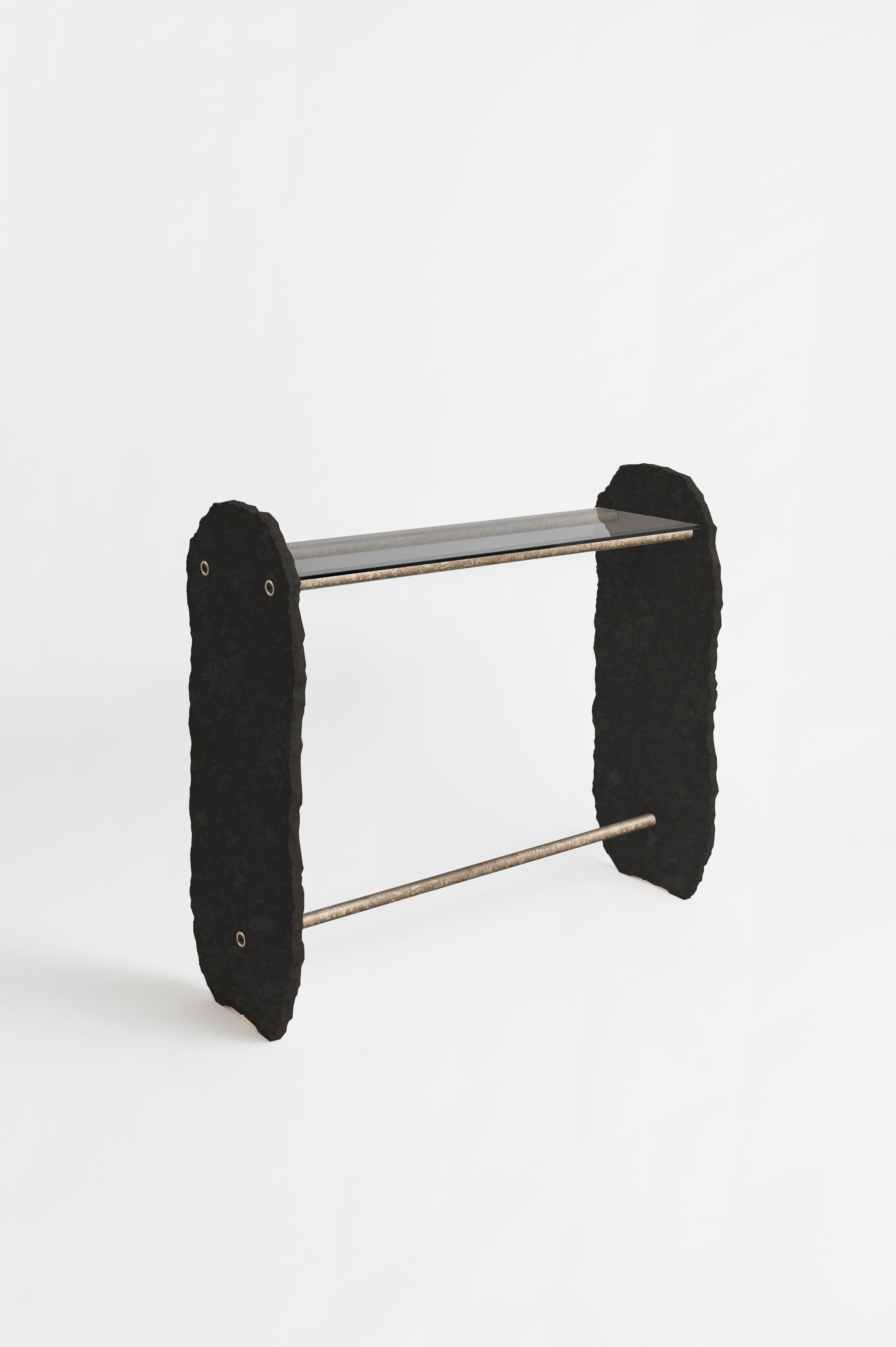 Stoique stole console signed by Fre´de´ric Saulou
Materials: Black stone, Grey smoked glass, metal powder-coated or engraved patinated brass.
Dimensions: H 110 x 40 x 110 cm.

