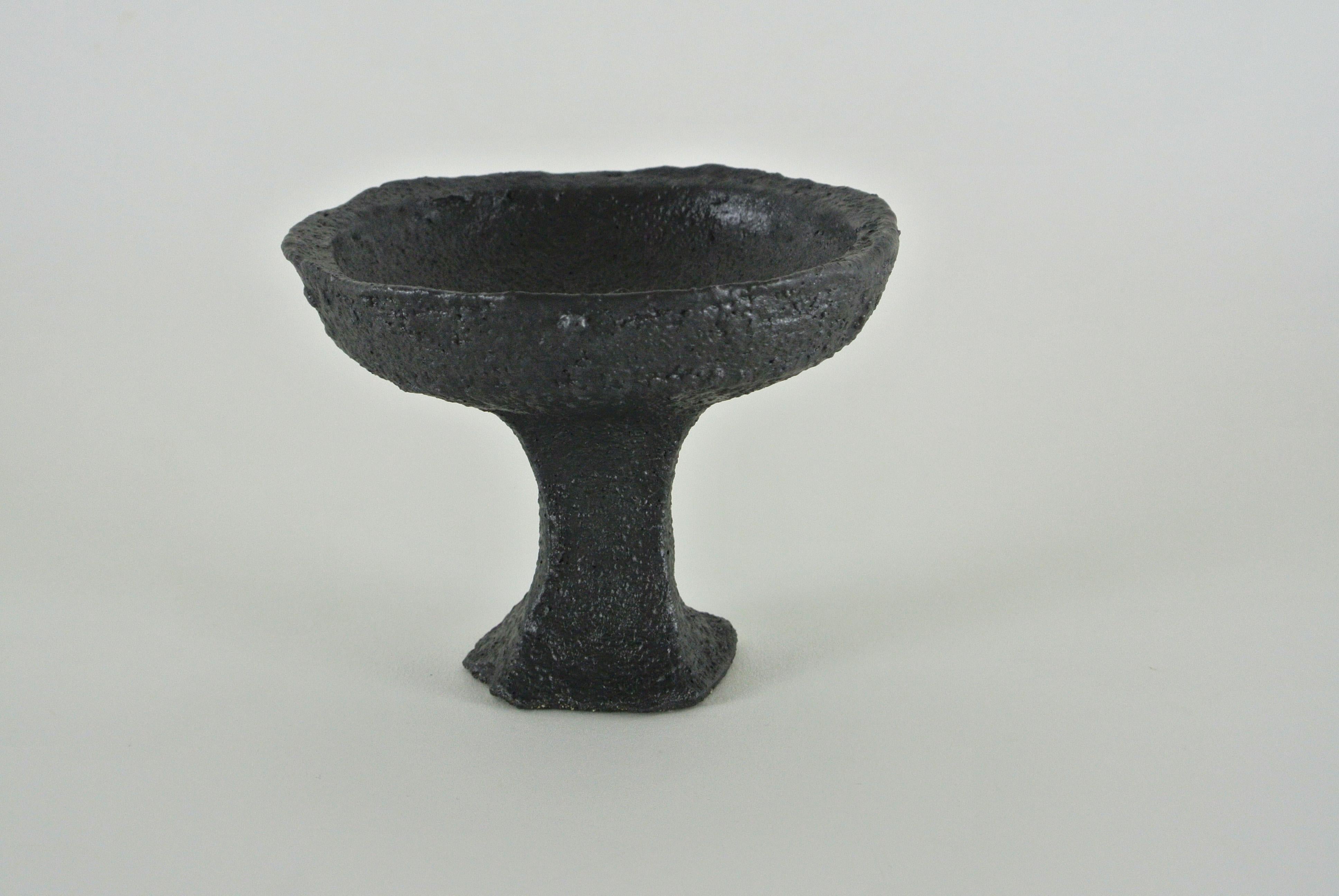 Black, rough stoneware goblet with black metallic glaze. Slightly asymmetric shape and visible fire sand structure on the surface.