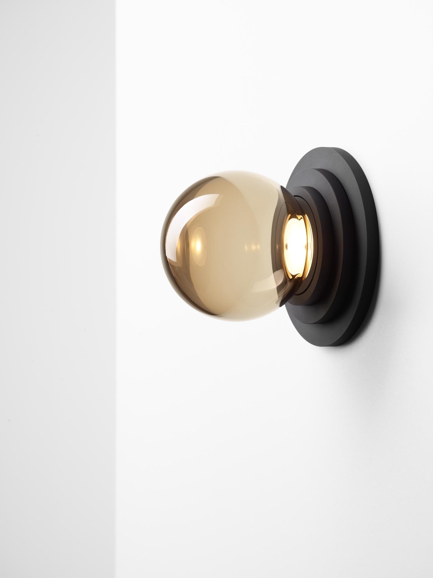 Black Stratos mini ball wall light by Dechem Studio
Dimensions: D 12 x H 14 cm
Materials: Aluminum, glass.
Also available: Different colours available

Different shapes of capsules and spheres contrast with anodized alloy fixtures, creating a