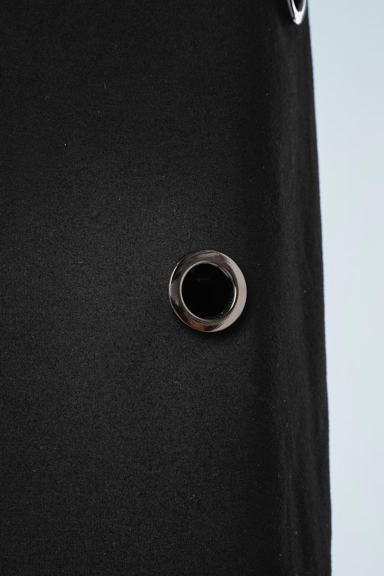 Jupe crayon en jersey noir avec œillets métalliques. Doublure en jersey fin et extensible. 
TAILLE S.I.M. 