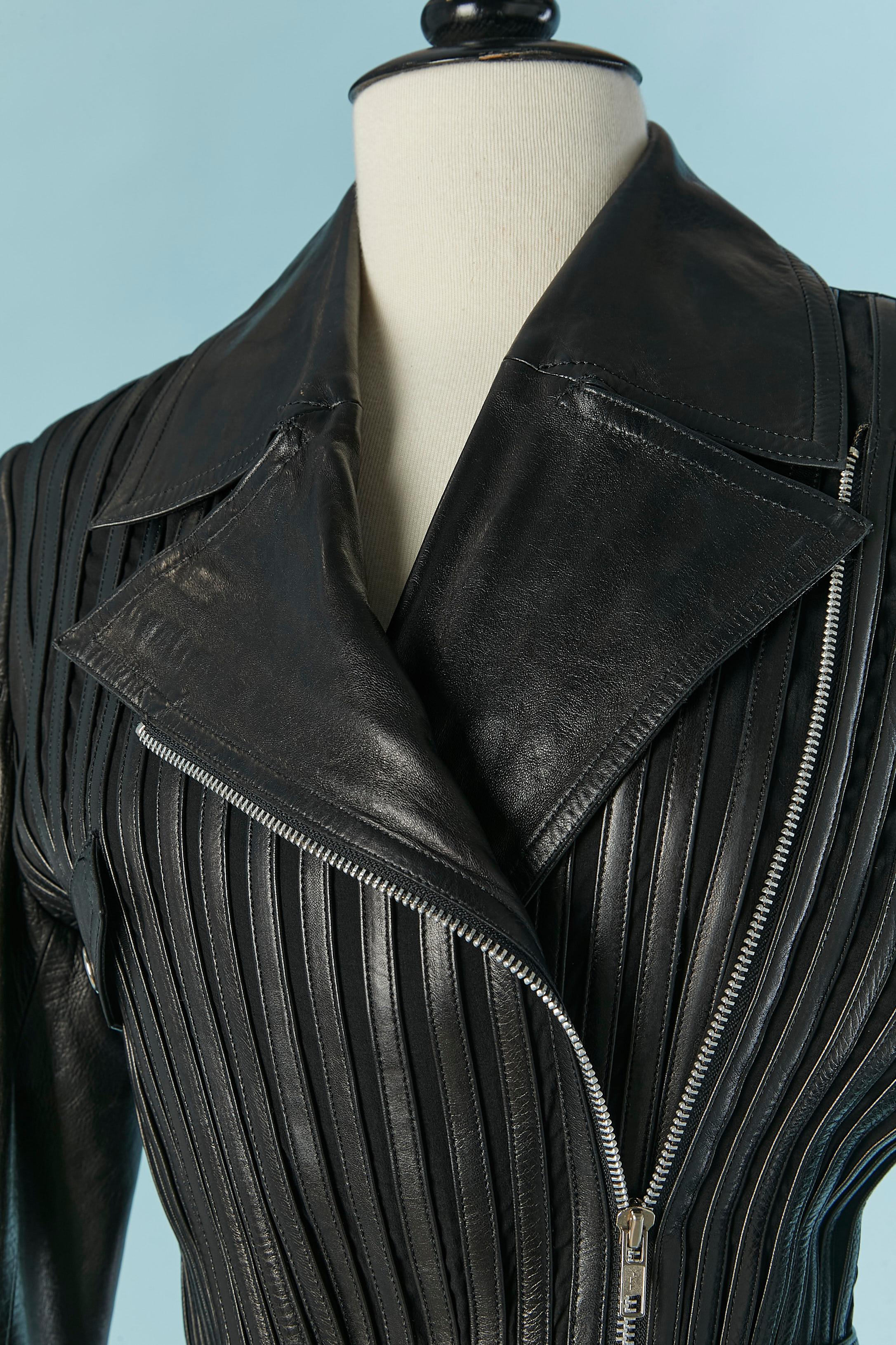 Veste en cuir extensible noir (avec ruban de cuir sur le devant et le dos) sur une base de soie extensible. Doublure en satin probablement en rayonne.  ceinture avec fermeture à boucle . Poche décorative (seulement le rabat, pas de pochette)