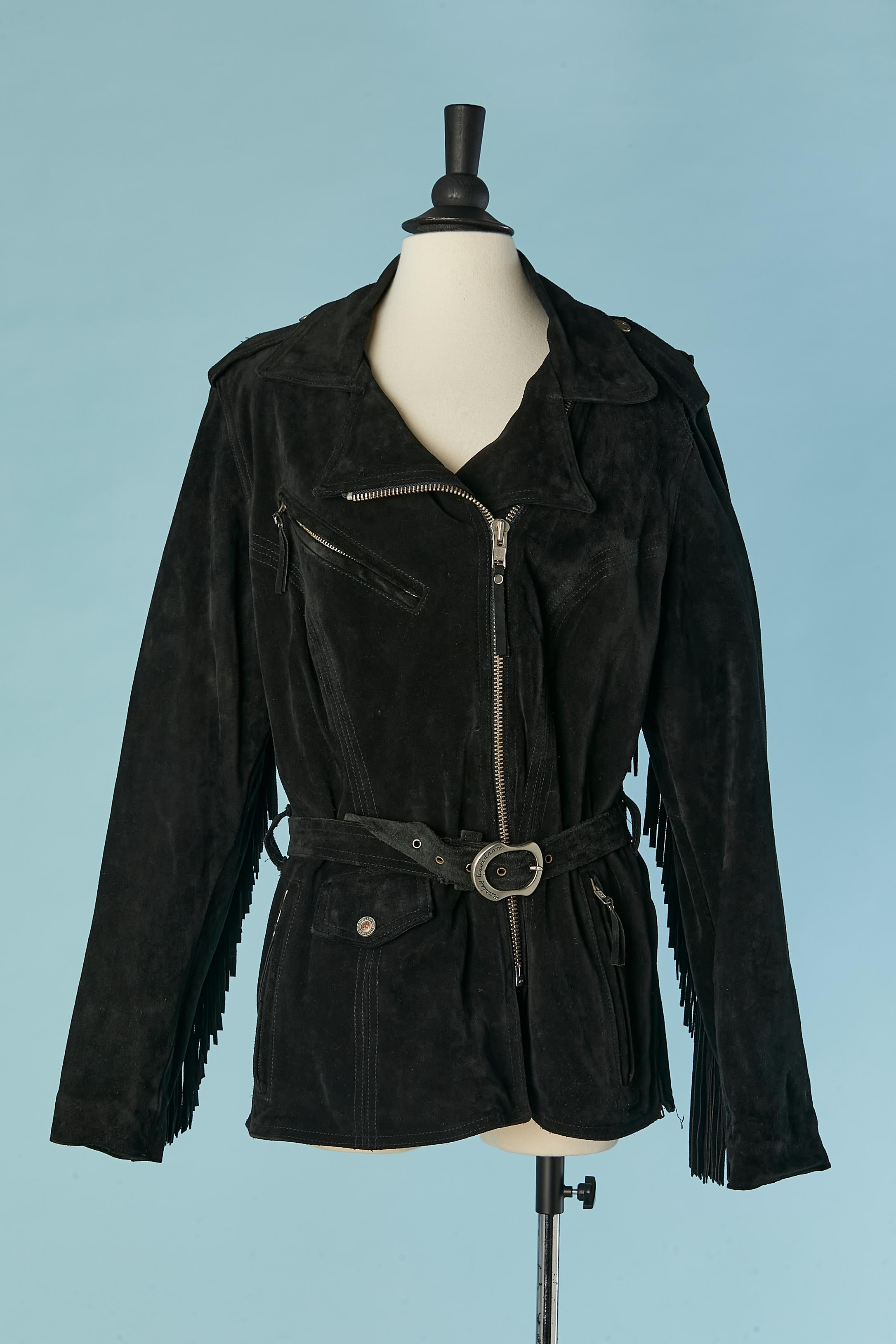 Black suede biker jacket with fringes sleeves and back. Polyester lining. Suede belt with silver metal buckle. Zip closure on the middle front + on the cuffs. 2 outside pockets with zip closure and one with branded snap closure. One inside pocket