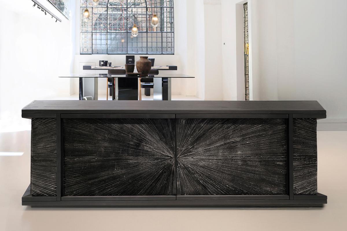 This striking console is crafted in sandblasted, black-stained fir wood, showcasing a rich, sculptural grain that highlights the natural depth of the material. The drawers are wrapped in patinated cast aluminum, introducing a refined metallic