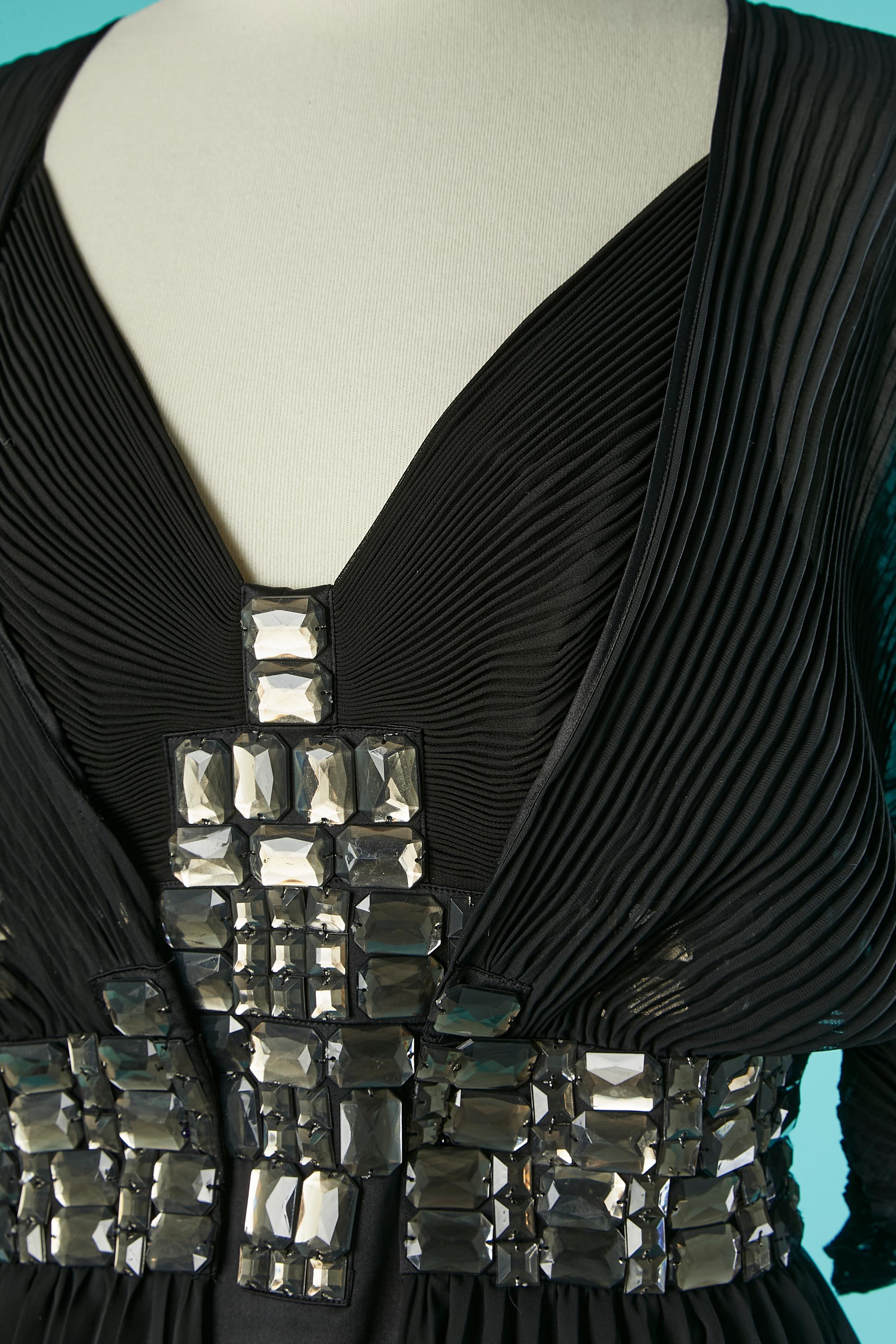 Black sun-pleat jacket and evening dress ensemble with rhinestone cabochon embellishment . Main fabric: 100% polyester. 
Final touches : 95% silk, 5% elastane 
Zip on the left side of the jacket ( but I dont understand the use of it?) 
Zip on the