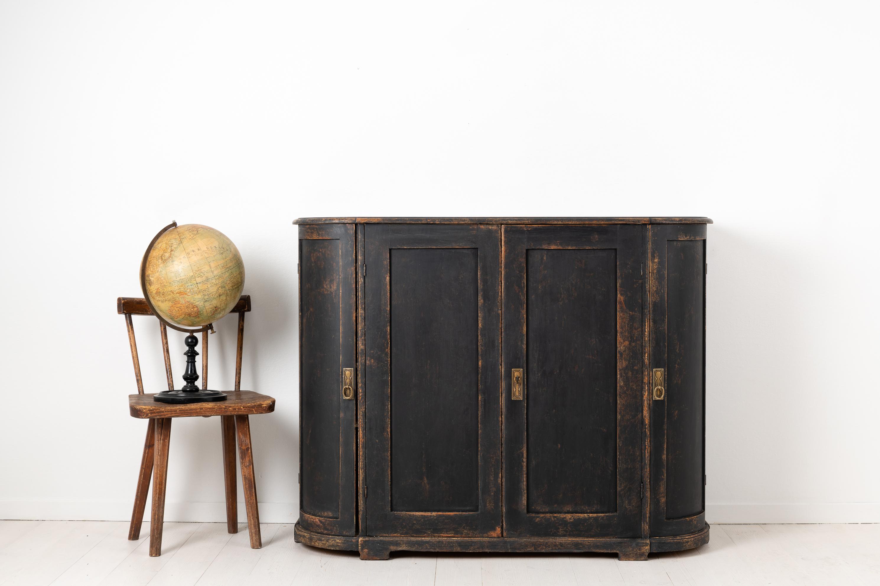 Swedish sideboard in Gustavian style with a curved front and distressed black paint. The sideboard is from the 1820s to 1840s and has four doors where the two doors at the end are rounded. The interiors has shelves and two drawers behind the front