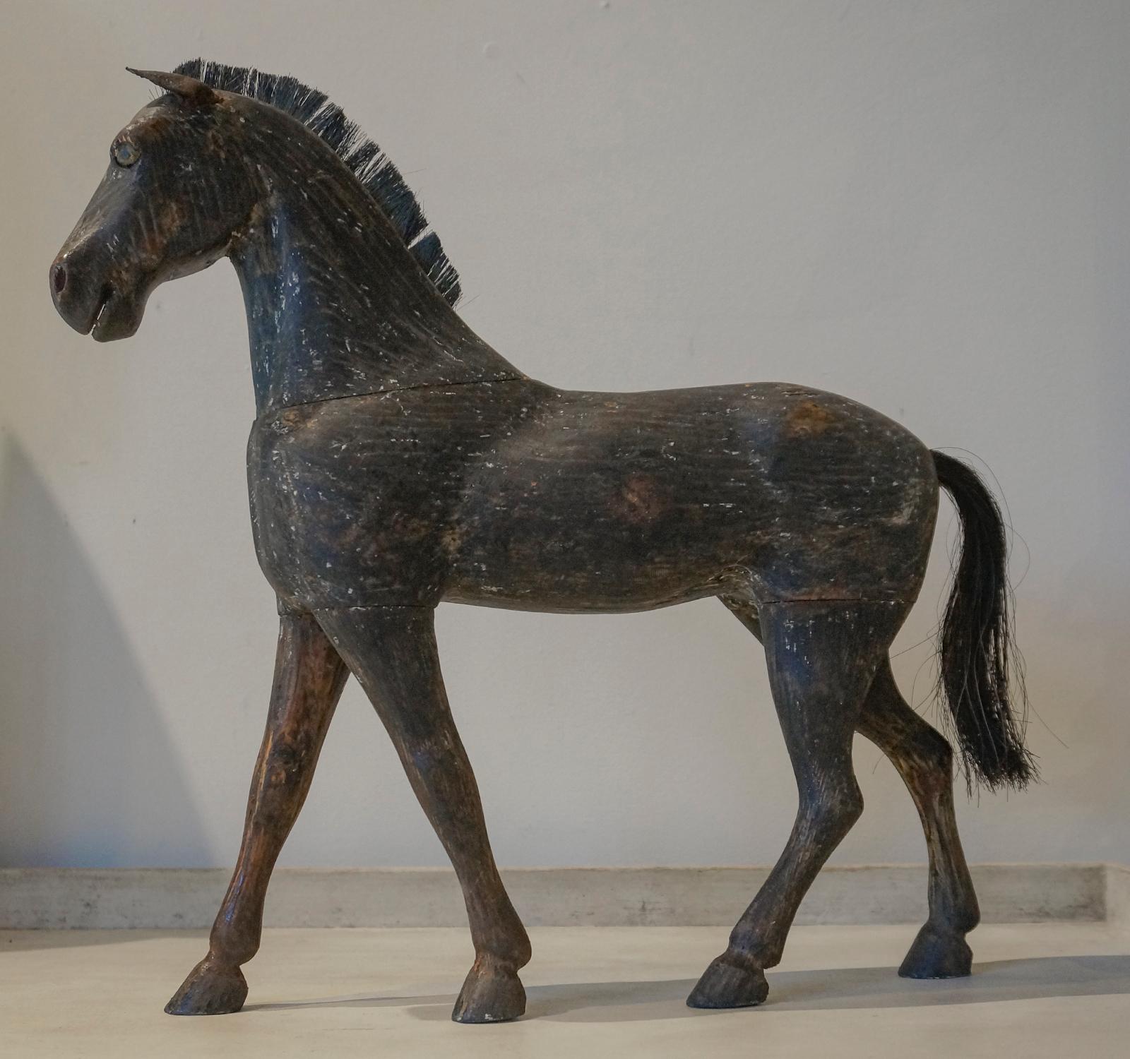 Carved toy horse, Sweden, circa 1880, which retains its original black painted surface. Leather ears and horsehair mane and tail.