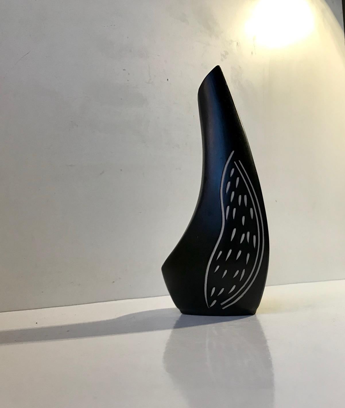Biomorphic, tactile vase almost shaped like the torso of a standing bird. It has a subtle black main glaze and is decorated by hand with white stripes. It was designed and studio made by the Danish ceramist Elisabeth Loholt during the early 1960s in
