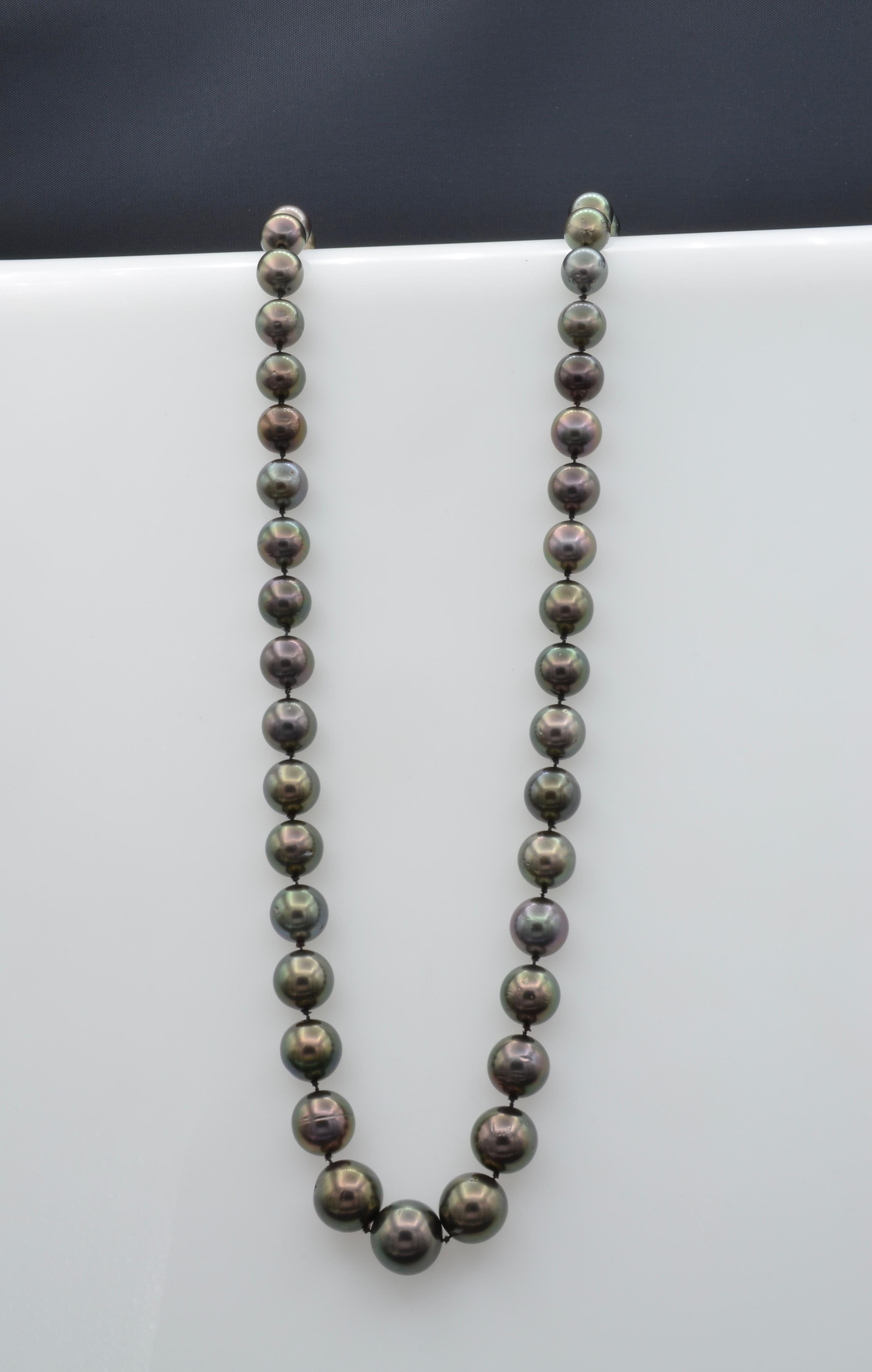 This luminous graduated black Tahitian pearl necklace has a ruby and diamond clasp set in 14k yellow gold. This classic and iconic pearl strand is a collectors dream. All of the pearls are perfectly matched and have a deep luminous rainbow cast. You