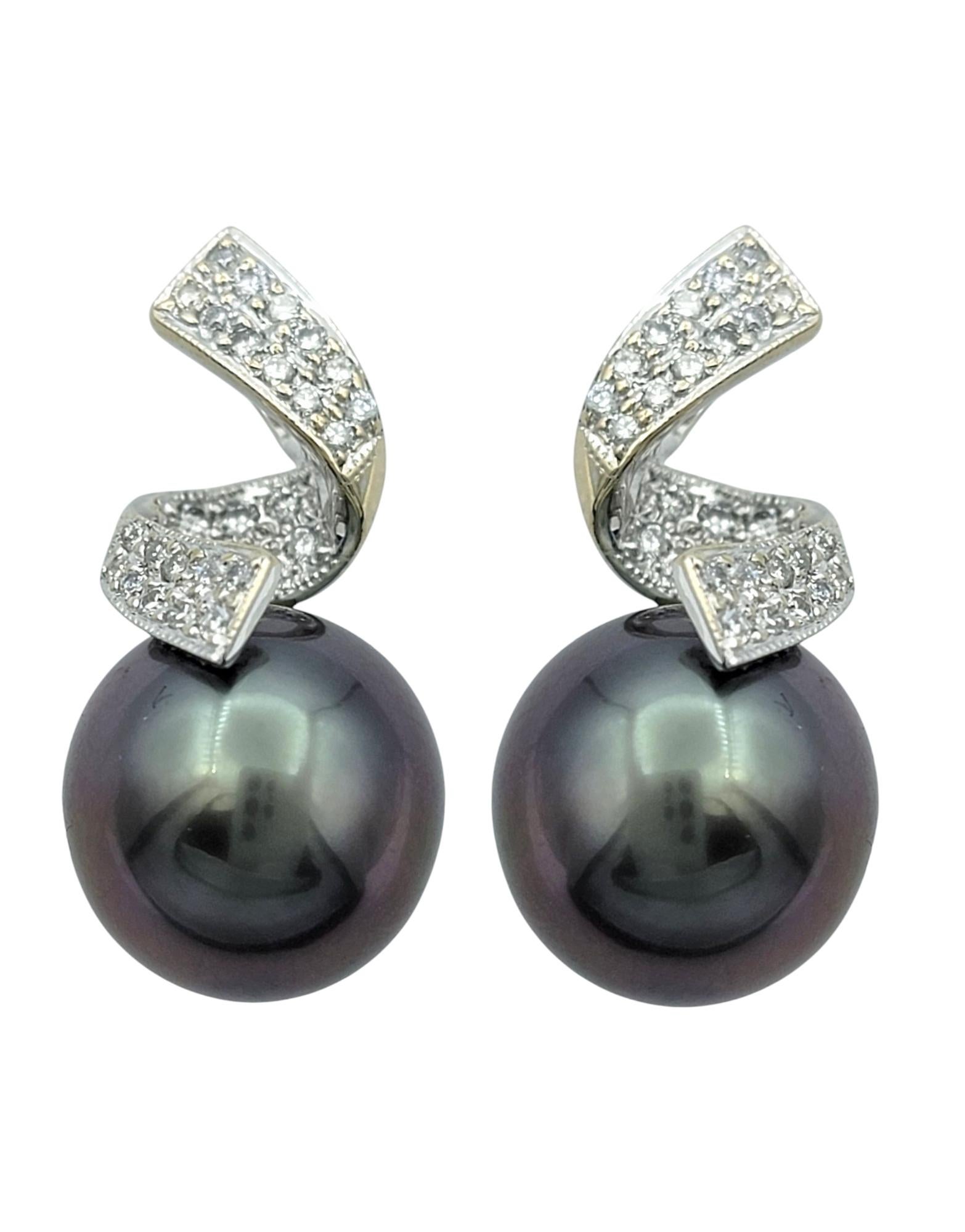 Estos sofisticados pendientes exhiben dos luminosas perlas de Tahití, cada una de ellas con un intenso tono negro iridiscente. Su forma casi redonda y su gran brillo crean un lujoso resplandor, añadiendo profundidad y elegancia a su llamativo