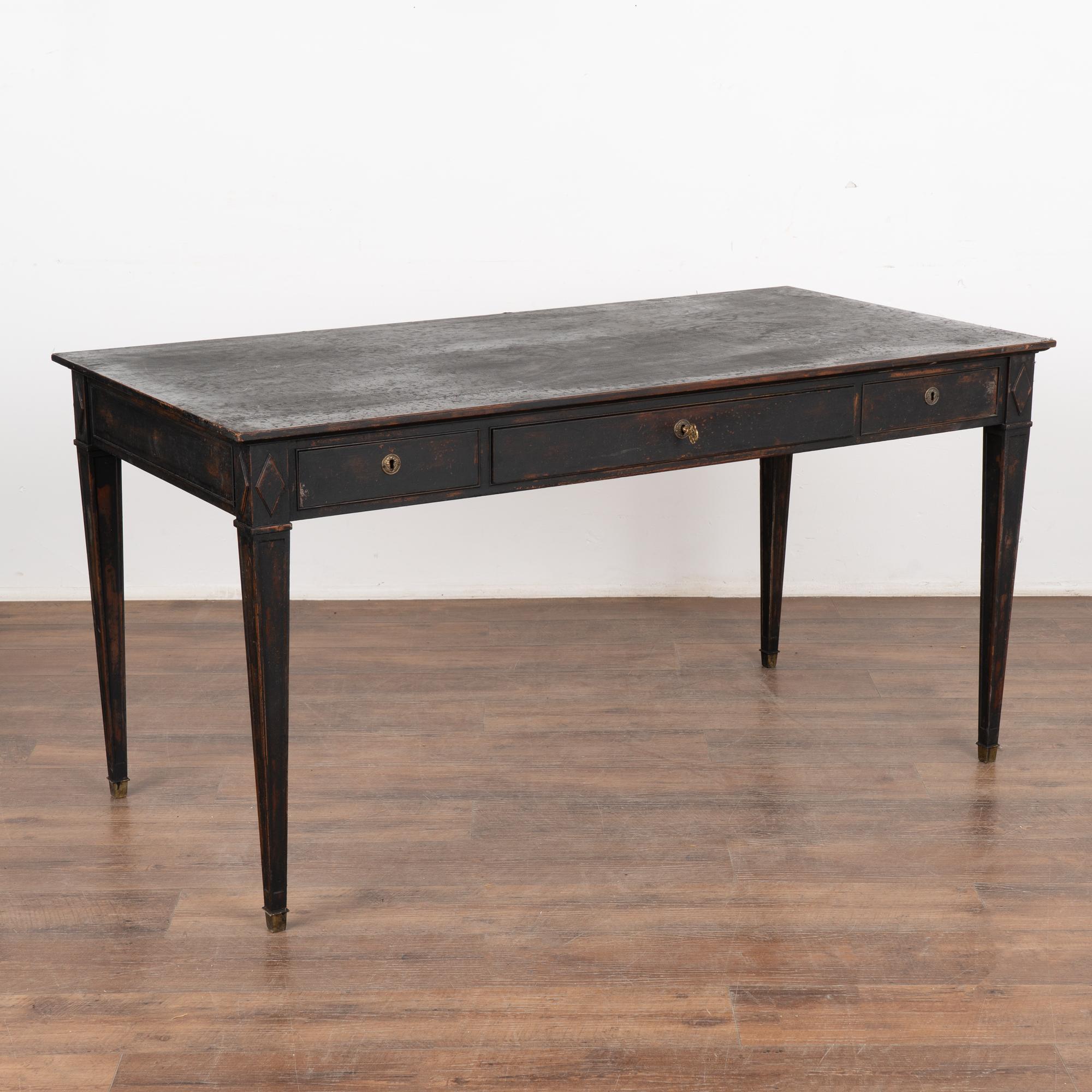 Three drawer pine desk with tapered legs topped by diamond accent.
Restored, handsome black painted finish is lightly distressed fitting the age and grace of this lovely writing table. 
The old locks on each of the three drawers still function with