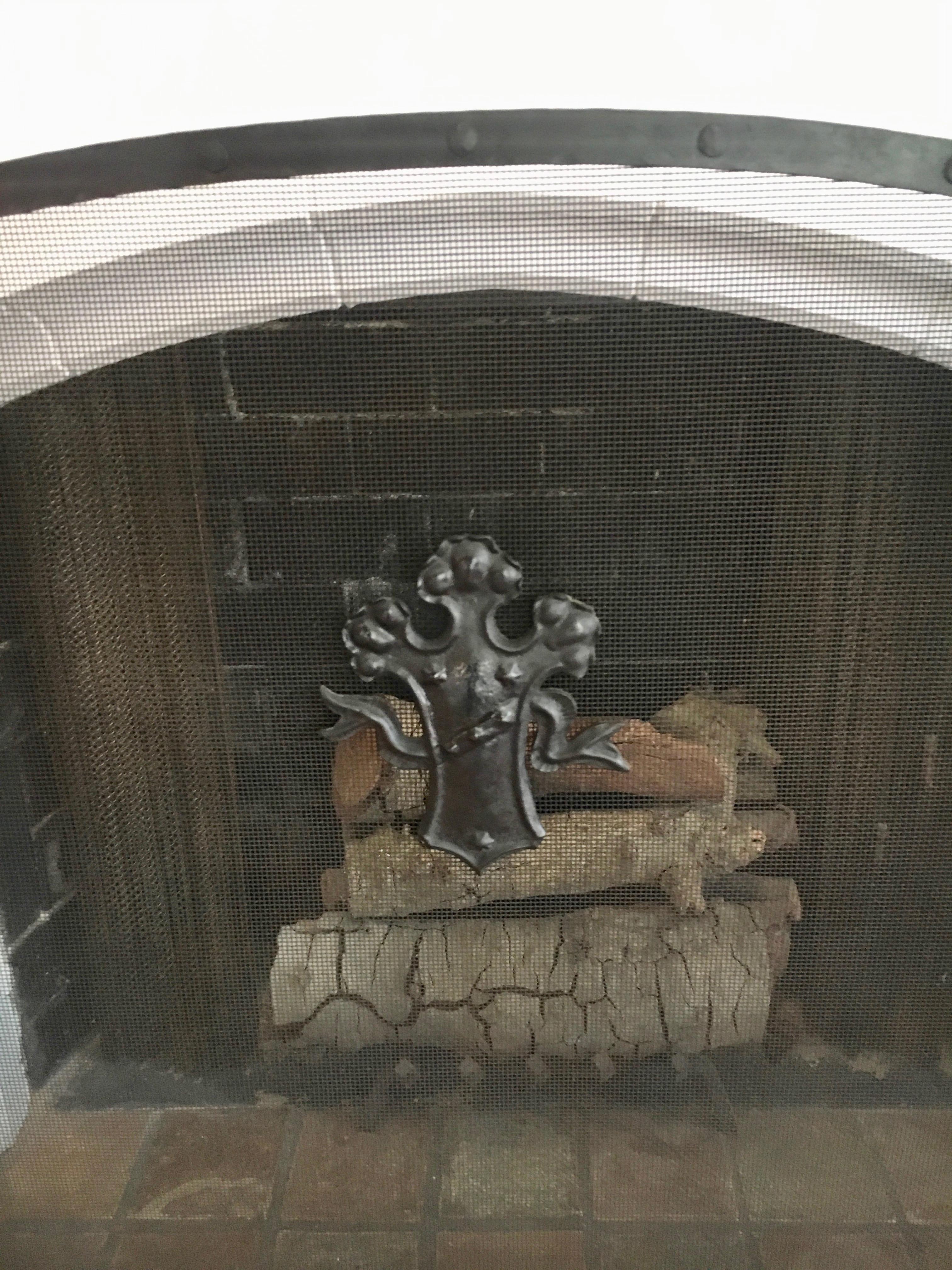 Beautiful wrought iron framed fireplace screen with black mesh, crest and scroll detail on side panels.

The screen works well in any room - especially with a palladium or arched fireplace - with side folding panels the screen easily can adjust to