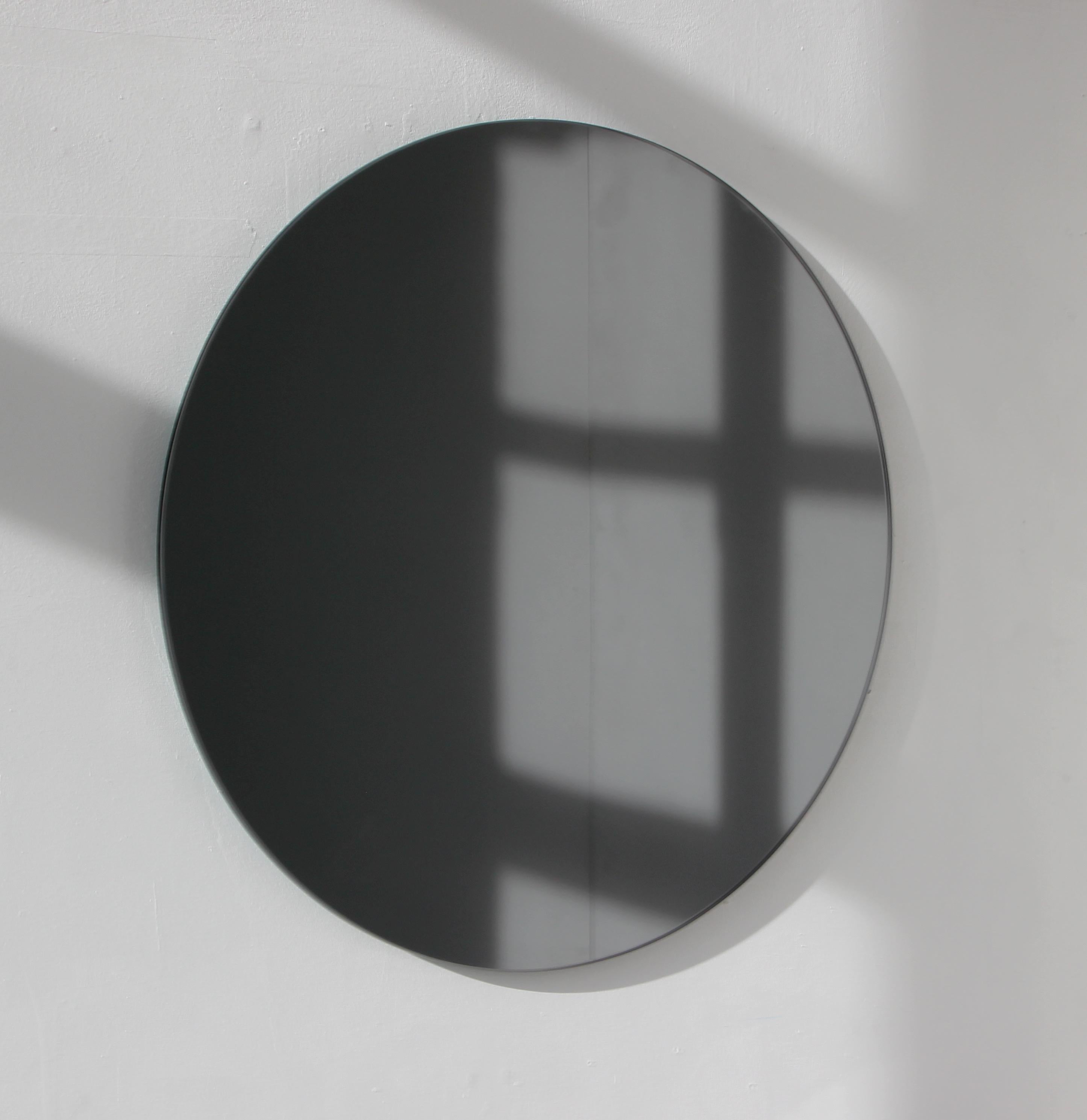 Charmanter und minimalistischer runder rahmenloser schwarz getönter Spiegel mit Schwebeeffekt. Hochwertiges Design, das dafür sorgt, dass der Spiegel perfekt parallel zur Wand steht. Entworfen und hergestellt in London, UK.

Ausgestattet mit