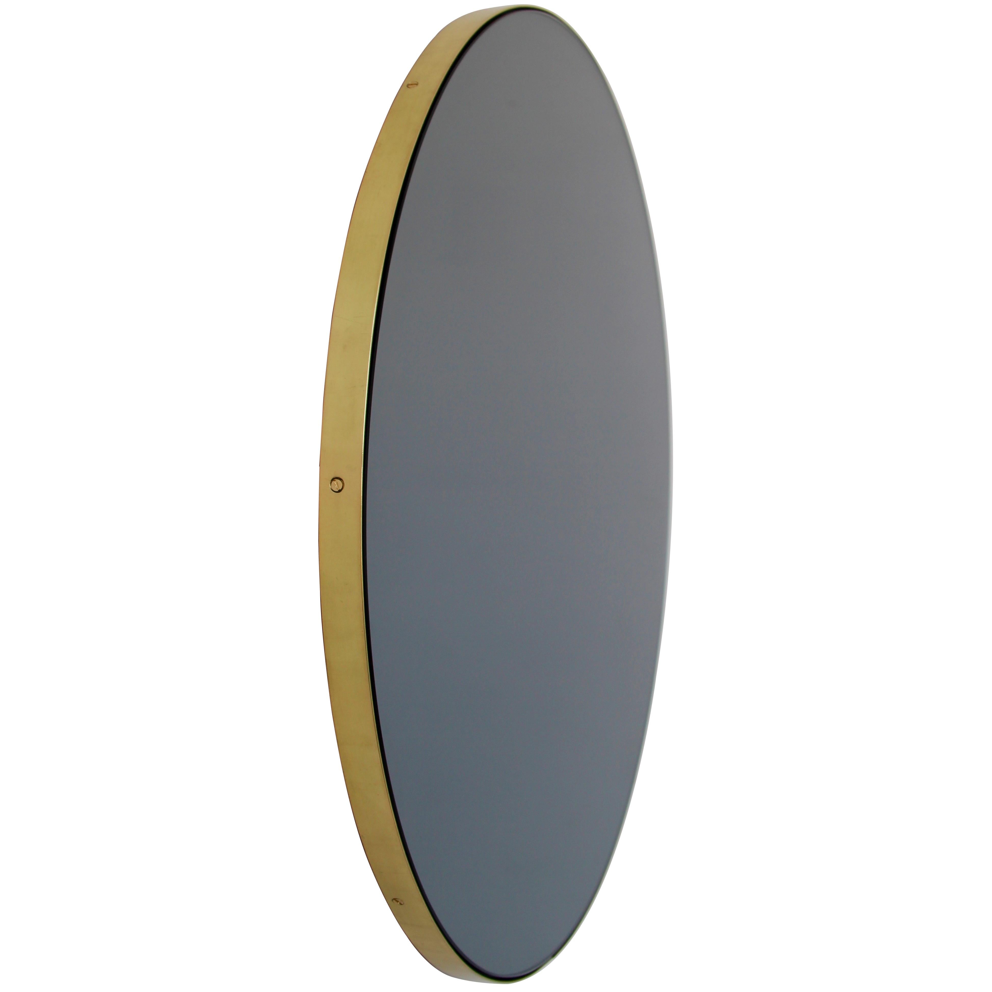 Minimalist black tinted round mirror with an elegant solid brushed brass frame. The detailing and finish, including visible brass screws, emphasise the crafty and quality feel of the mirror, a true signature of our brand. Designed and handcrafted in
