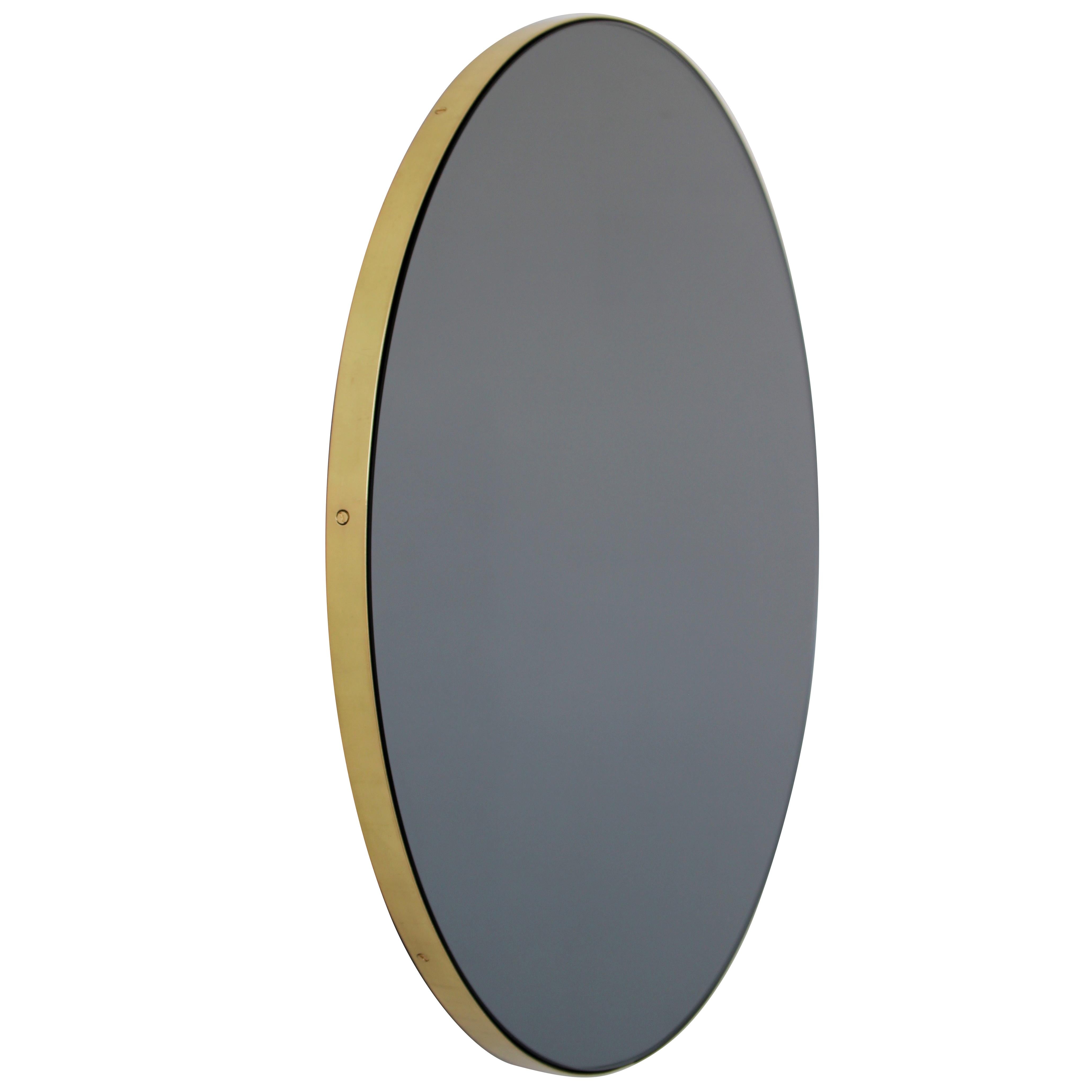 Minimalist black tinted round mirror with a minimalist solid brushed brass frame. The detailing and finish, including visible brass screws, emphasise the crafty and quality feel of the mirror, a true signature of our brand. Designed and made in