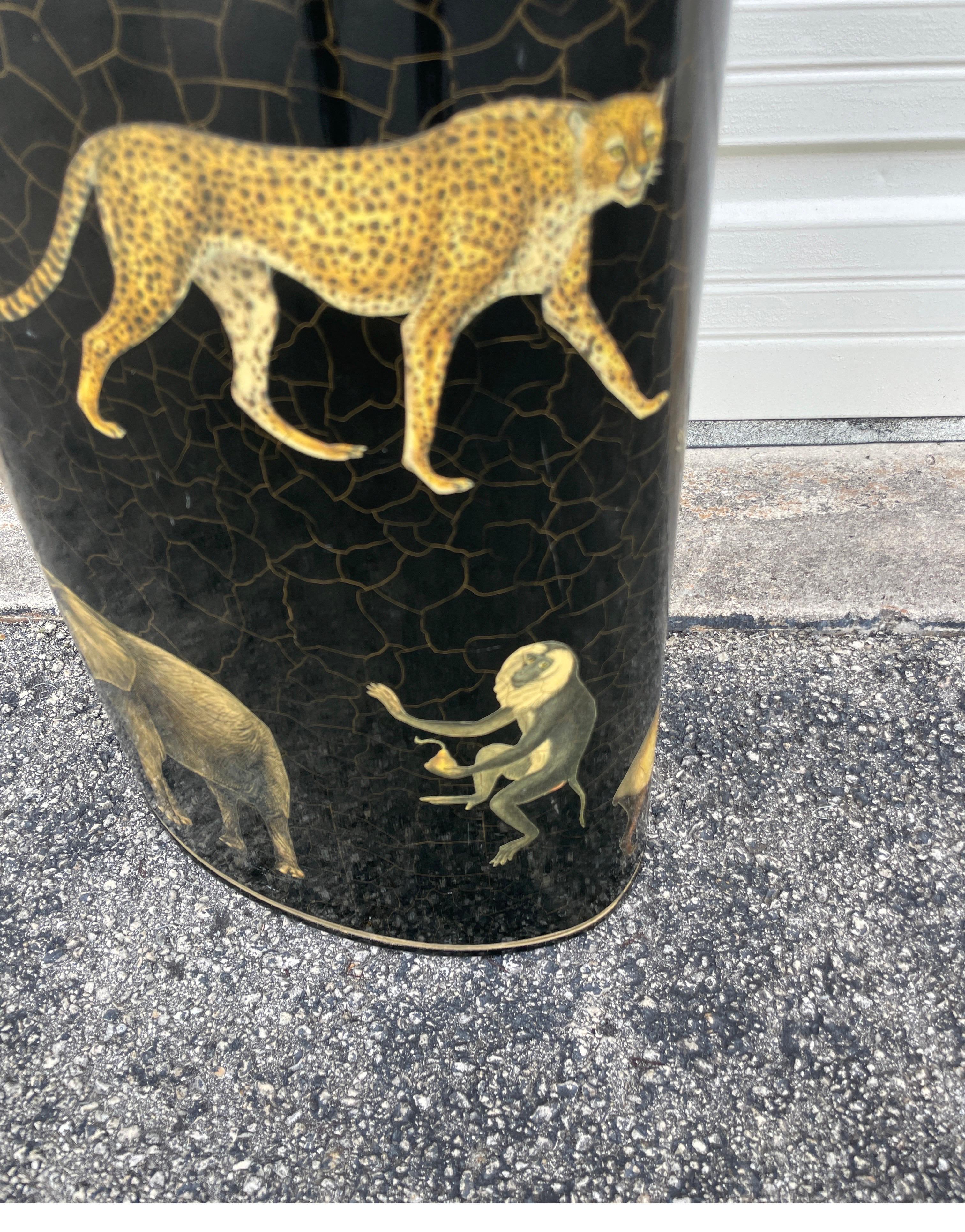 Fabuleux porte-parapluie en tole découpé représentant des girafes, des éléphants, des léopards, des lions, des hippopotames et des singes sur un fond noir.