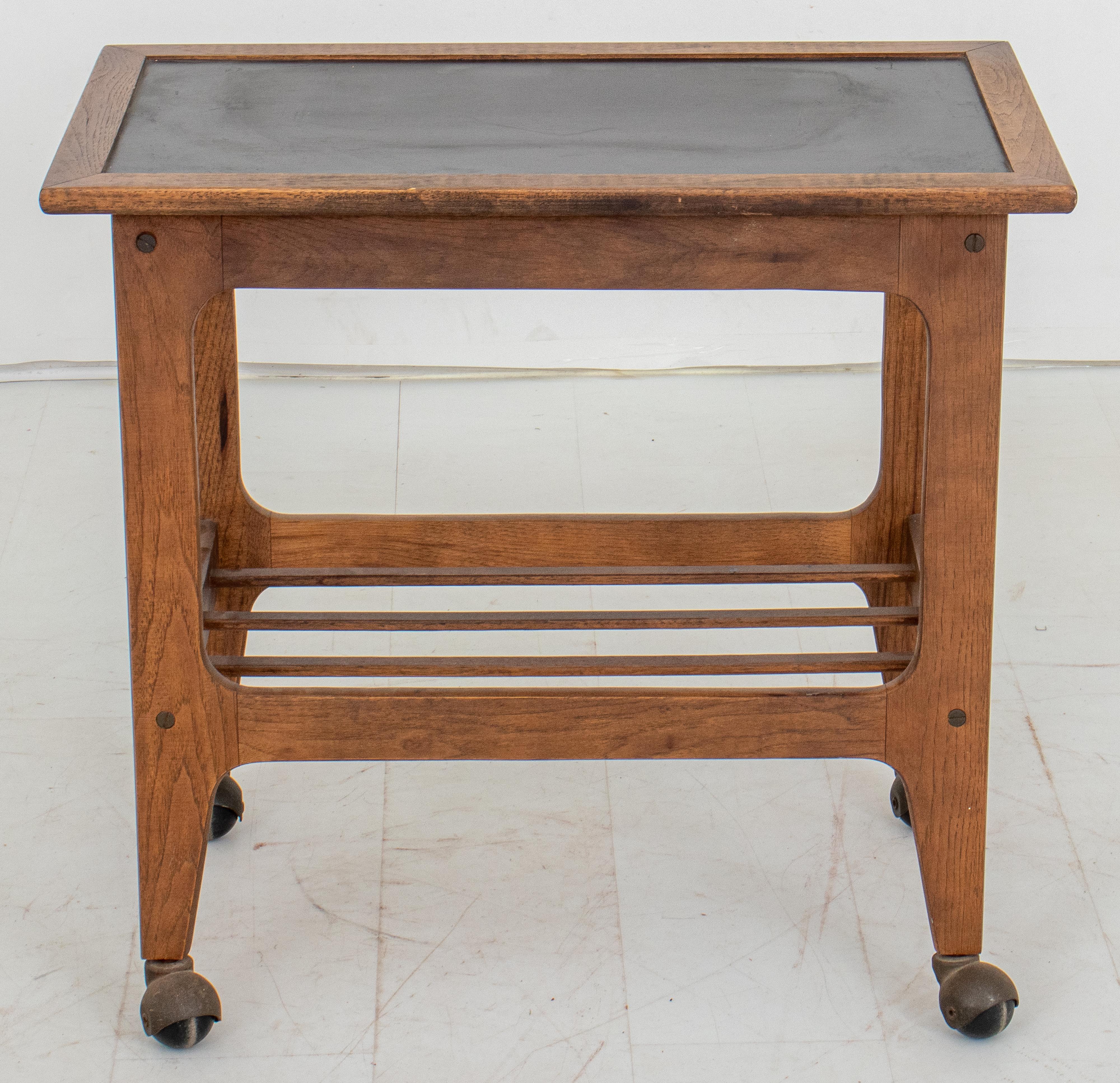 Black topped wooden rolling table bar cart, rectangular with four square legs conjoined by a spindled undertier terminating in four casters.

Dealer: S138XX