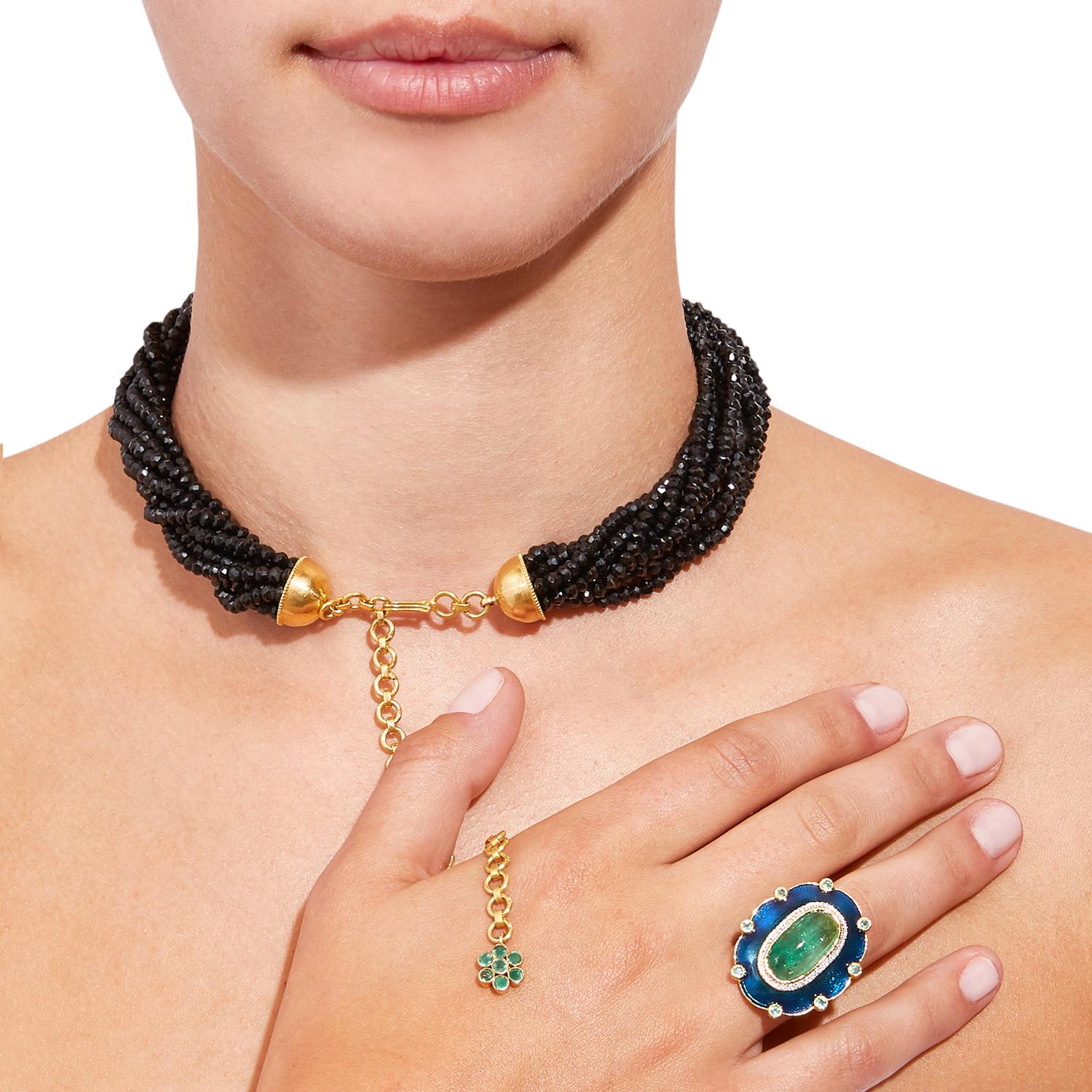 The drama and fire of natural black tourmalines is perfectly showcased in this tourmaline and emerald necklace featuring multiple strands of black tourmalines with an 18 karat gold chain closure and 4 inch long extender chain suspending an emerald