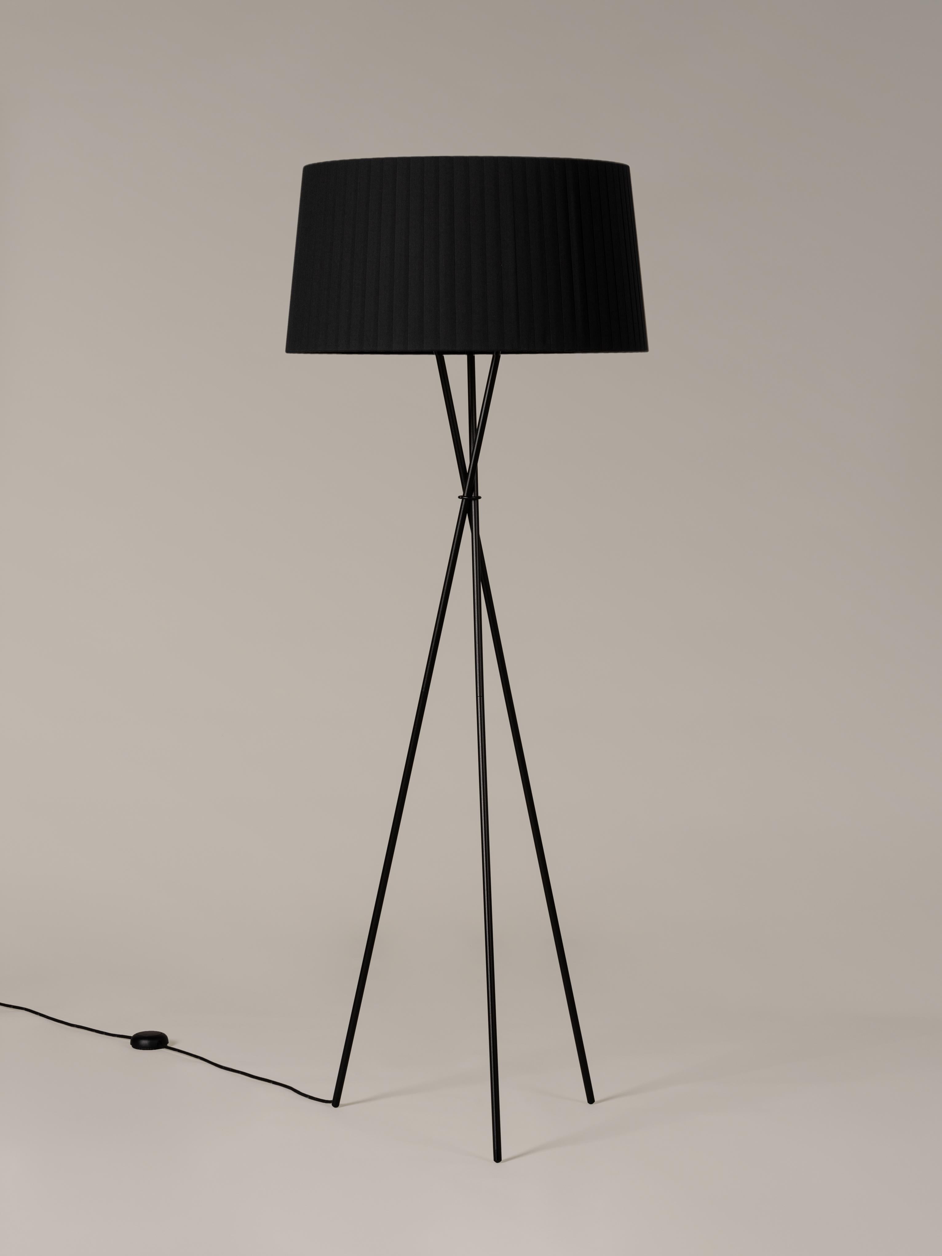 Black Trípode G5 floor lamp by Santa & Cole.
Dimensions: D 62 x H 168 cm.
Materials: metal, ribbon.
Available in other colors.

Trípode humanises neutral spaces with its colourful and functional sobriety. The shade is hand ribboned and its base