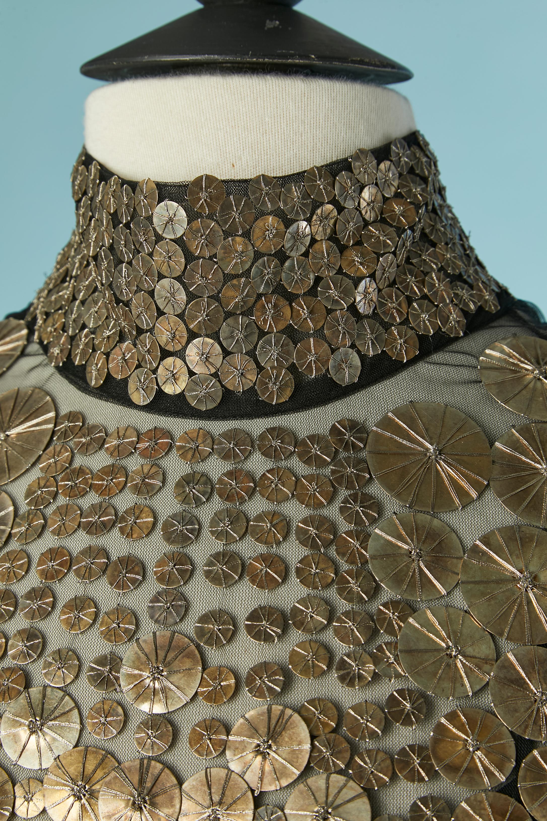 Schwarzer Tüll und goldene Metallpailletten-Applikationen, darunter ein schwarzes Unterkleid. 
Zusammensetzung des Obermaterials: 100% Nylon. Zusammensetzung der Pailletten: 80% metallisiert 20% Poly. Zusammensetzung des Unterkleides: 85% Acetat, 9%