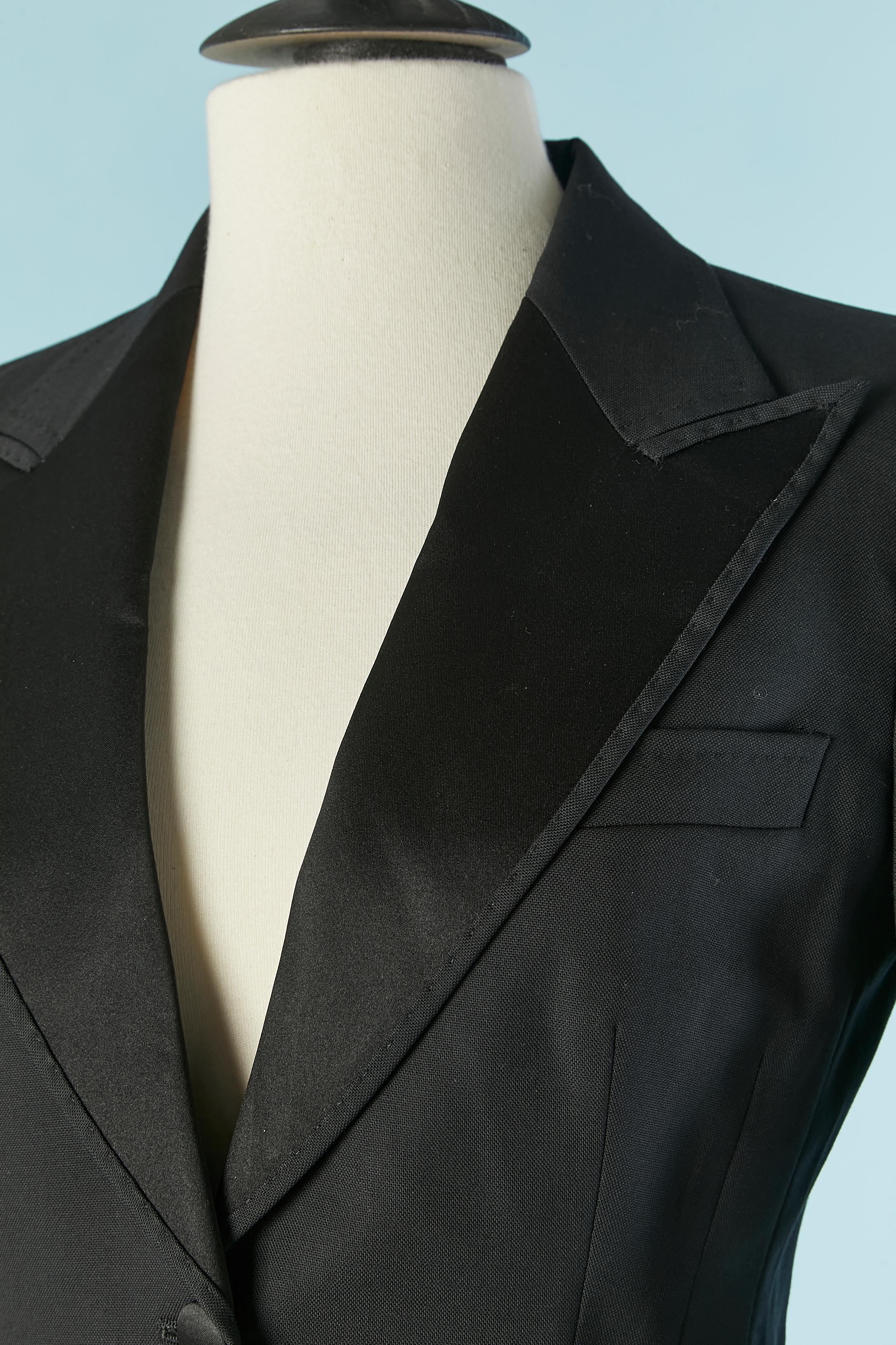 Black Tuxedo single-breasted jacket. The fabric composition tag has been cut but the main fabric is probably thin wool and the lining probably in silk or rayon.
Shoulder pad. Button covered with satin and buttonhole closure on the middle front.