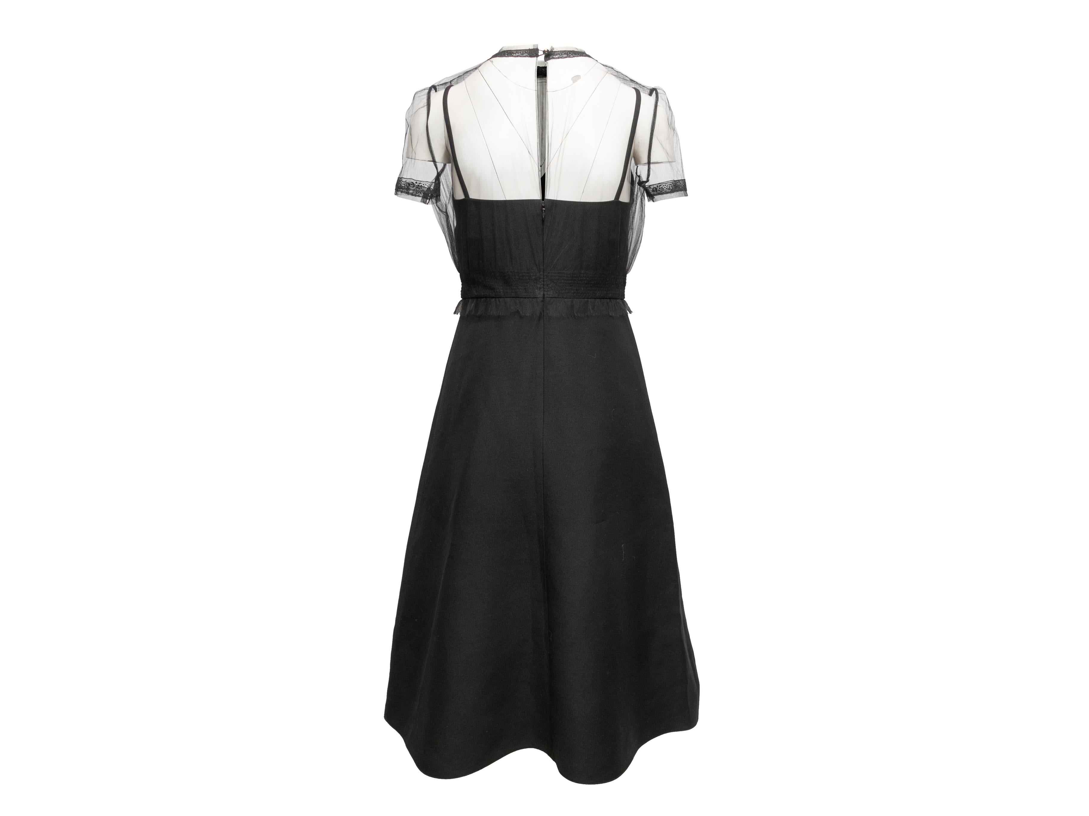 Black tulle and virgin wool-blend short sleeve cocktail dress by Valentino. Crew neck. Zip and button closures at back. 32