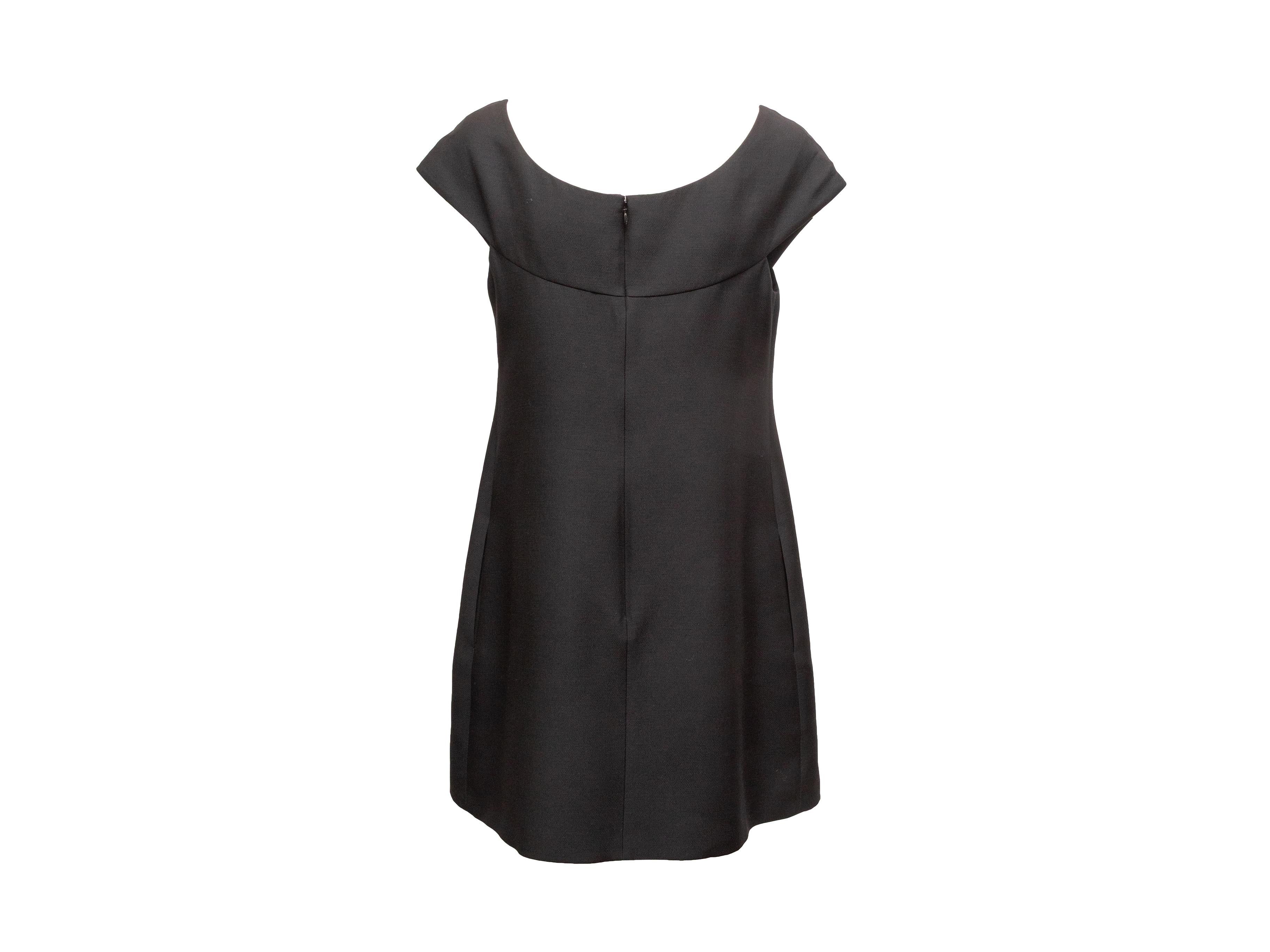 Mini abito nero in lana vergine e misto seta di Valentino. Scollo rotondo. Maniche corte. Fiocco sul davanti. Chiusura con zip sul retro. Seno 34