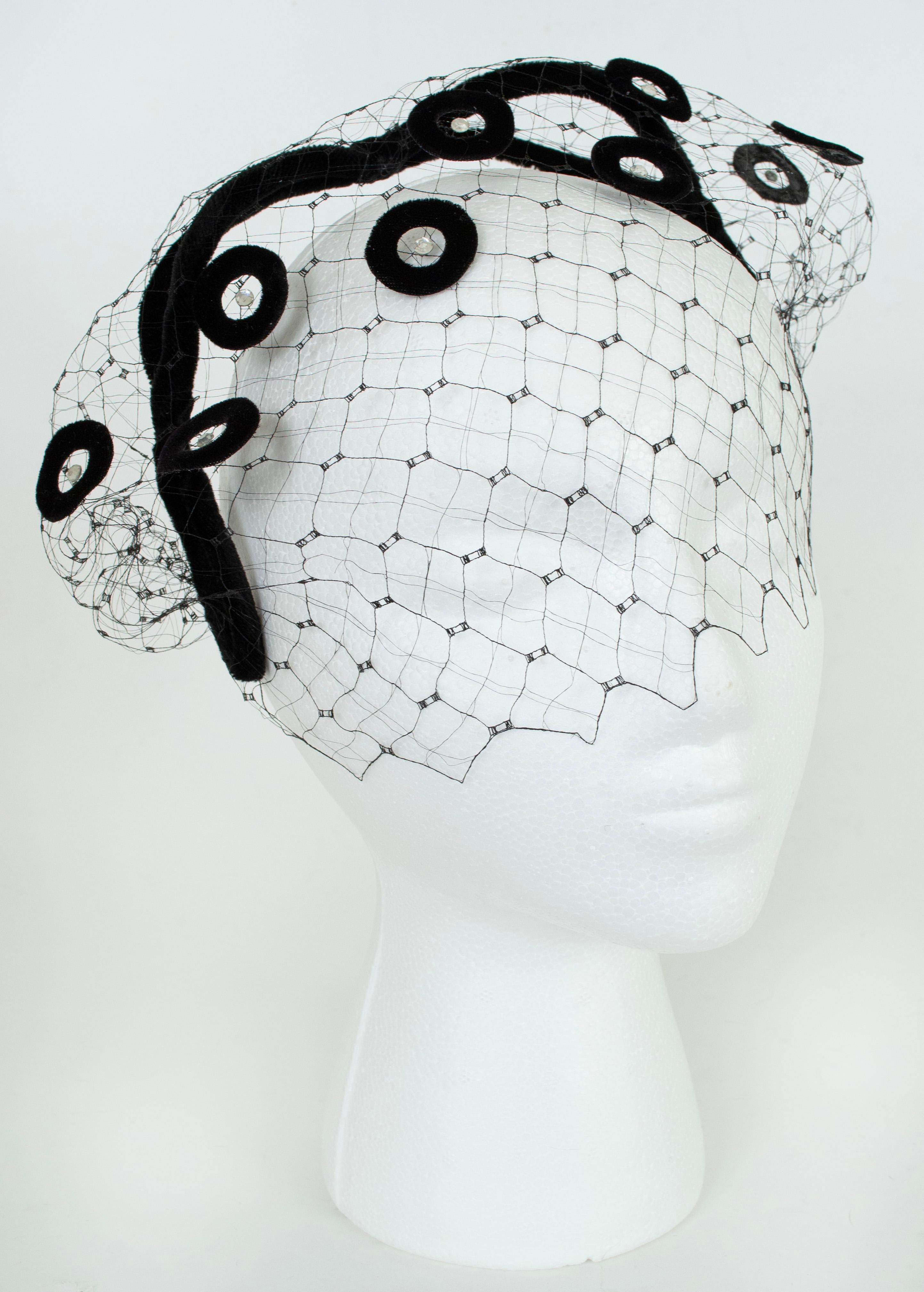 The mystery of a veil, the weightlessness of a fascinator, and the playfulness of Schiaparelli style appliqués in a single accessory. Next stop: a Henry Clarke portrait.

Black silk velvet openwork headband fascinator and veil studded with circular
