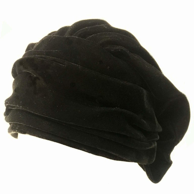1960s vintage black soft velvet turban hat with lining.
The detail of pleats and beautifully draped tucks to the back.

Measures approximately 57 cm when measure tape go around the interior  just inside the hat.