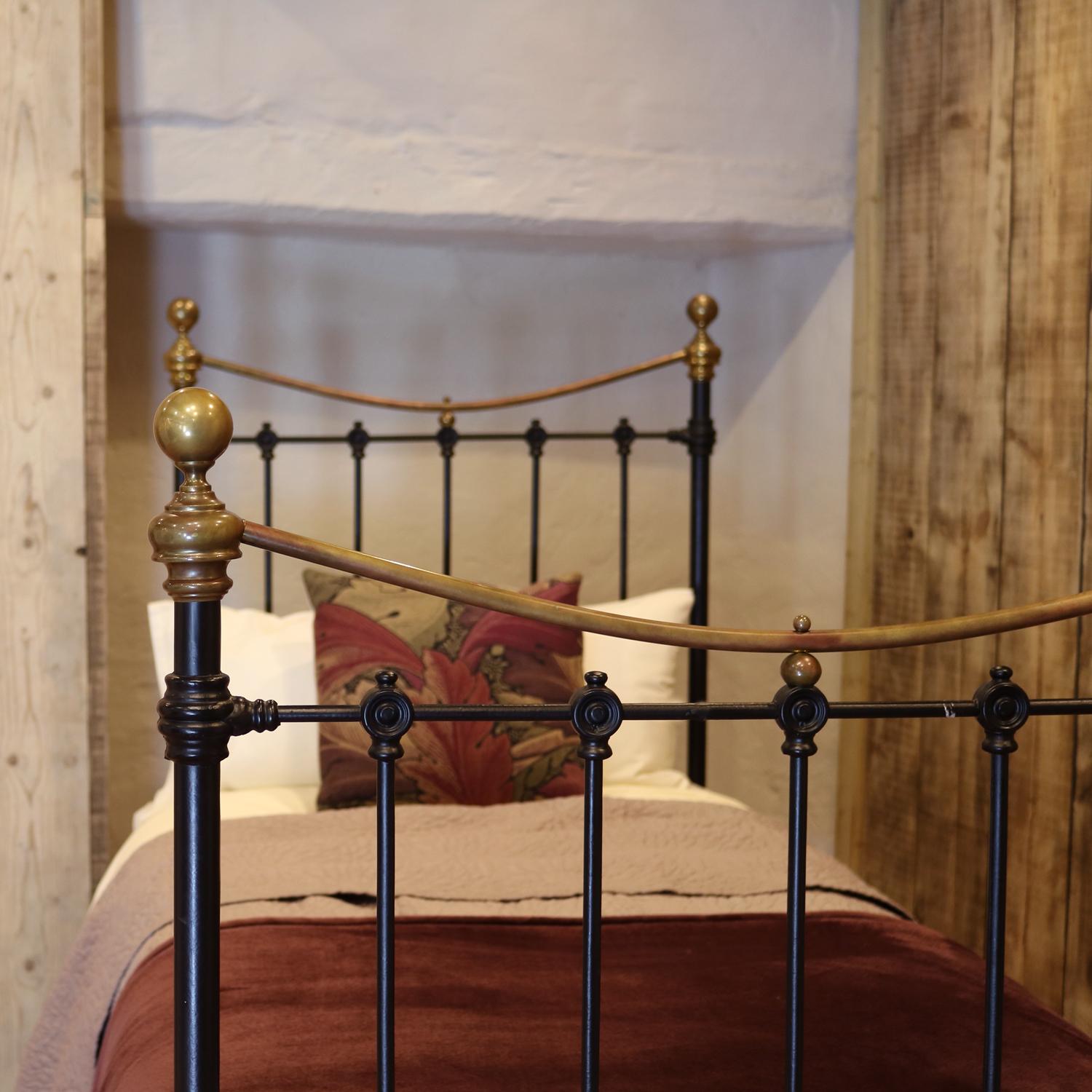 A traditional style Victorian antique bed painted in black, with curved brass top rails and brass knobs and understated castings. The iron posts drop down further than usual on the foot board, giving it an extra feature. 

The price is for the