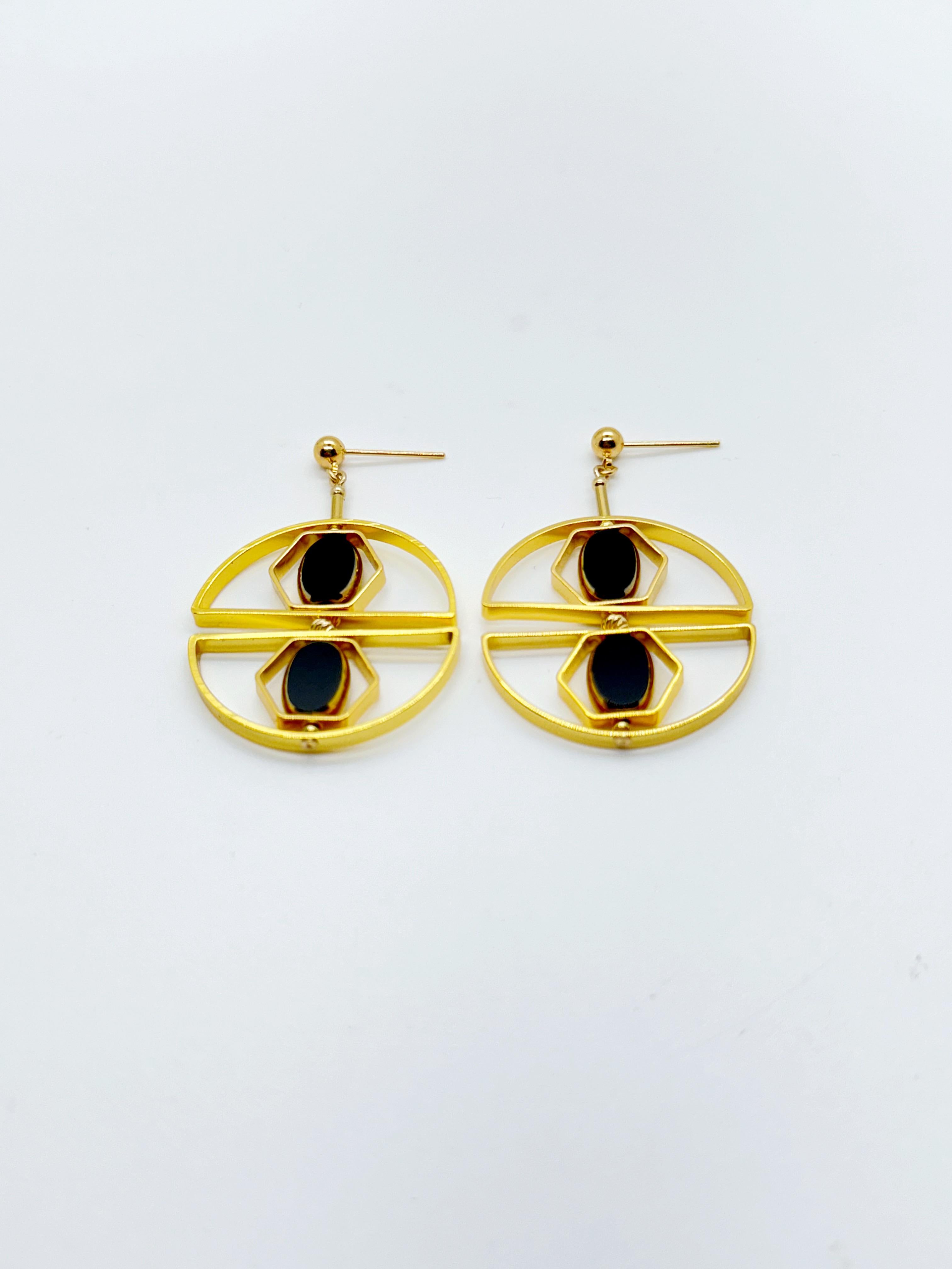 The earrings are light weight and are made to rotate and reposition with movement.

The earrings consist of black new old stock vintage German glass beads that are framed with 24K gold. The beads were hand-pressed during the 1920s-1960s in
