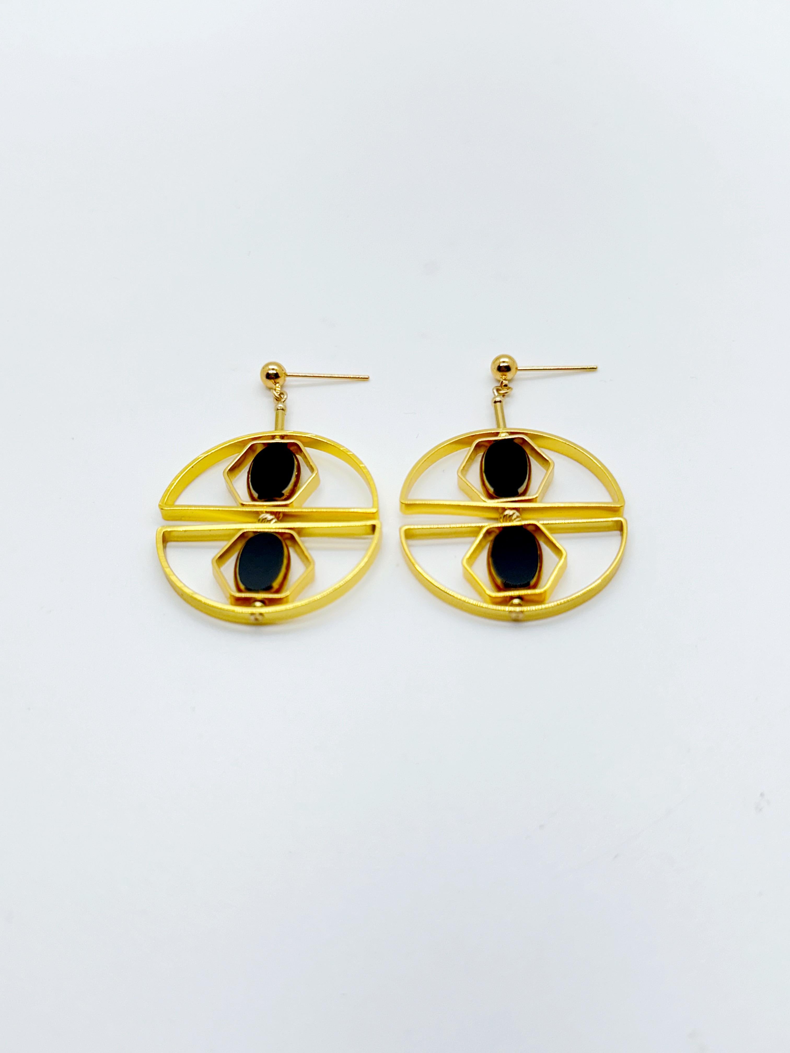 Les boucles d'oreilles sont légères et sont conçues pour tourner et se repositionner en fonction des mouvements.

Les boucles d'oreilles sont composées de perles de verre allemandes noires, neuves et anciennes, encadrées d'or 24K. Les perles ont été