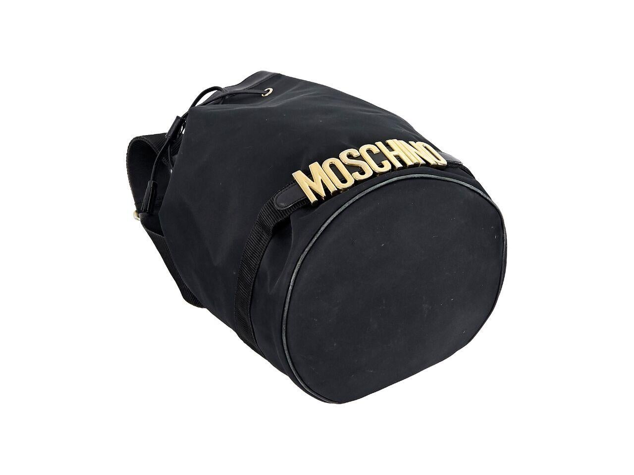 Product details:  Vintage black nylon bucket bag by Moschino.  Trimmed with leather.  Single adjustable shoulder strap.  Top drawstring closure.  Lined interior with inner attached zip pouch.  Logo charms accent bottom.  Goldtone hardware.  14