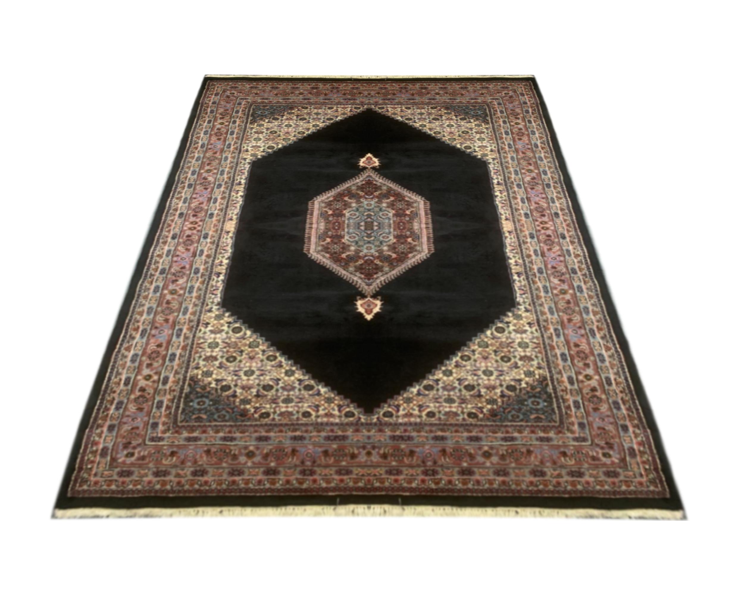 Ce tapis exquis fait à la main présente un remarquable motif géométrique en médaillon sur un champ noir audacieux, encadré par des bordures florales richement détaillées dans des tons de rouge, d'ivoire, de bleu et de beige. Tissé à la main avec un