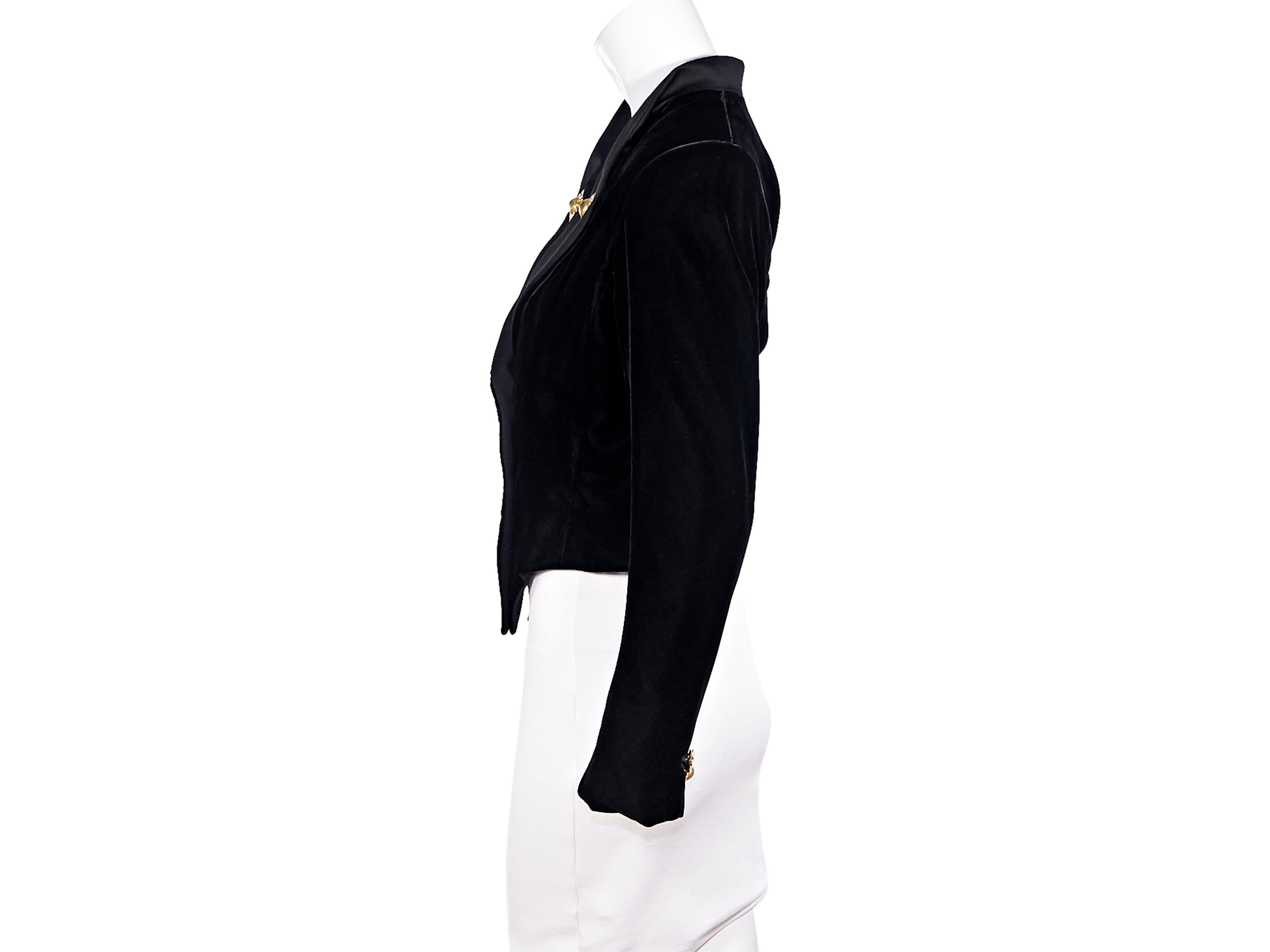 Product details:  Vintage black velvet cropped jacket by Yves Saint Laurent.  From the 1990s.  Accented with decorative buttons.  Satin lapel.  Long sleeves.  Button-front closure.  Seams create a flattering silhouette.  Goldtone hardware.  36