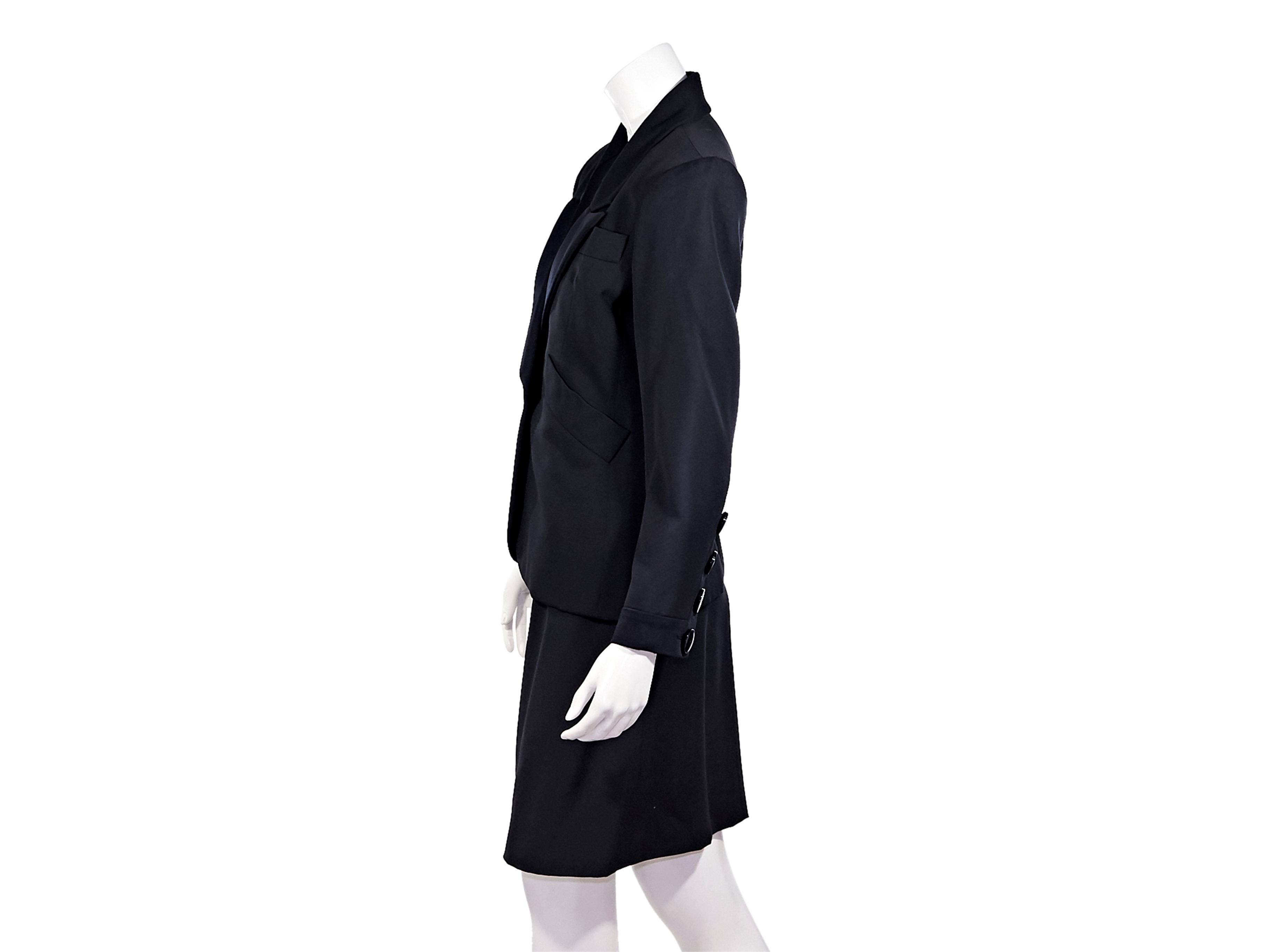 Product details:  Vintage black wool skirt suit set by Yves Saint Laurent.  Peaked satin lapel.  Long sleeves.  Four-button detail at cuffs.  Single-button closure.  Waist slide pockets.  Matching pencil skirt.  Banded waist.  Side button and zip